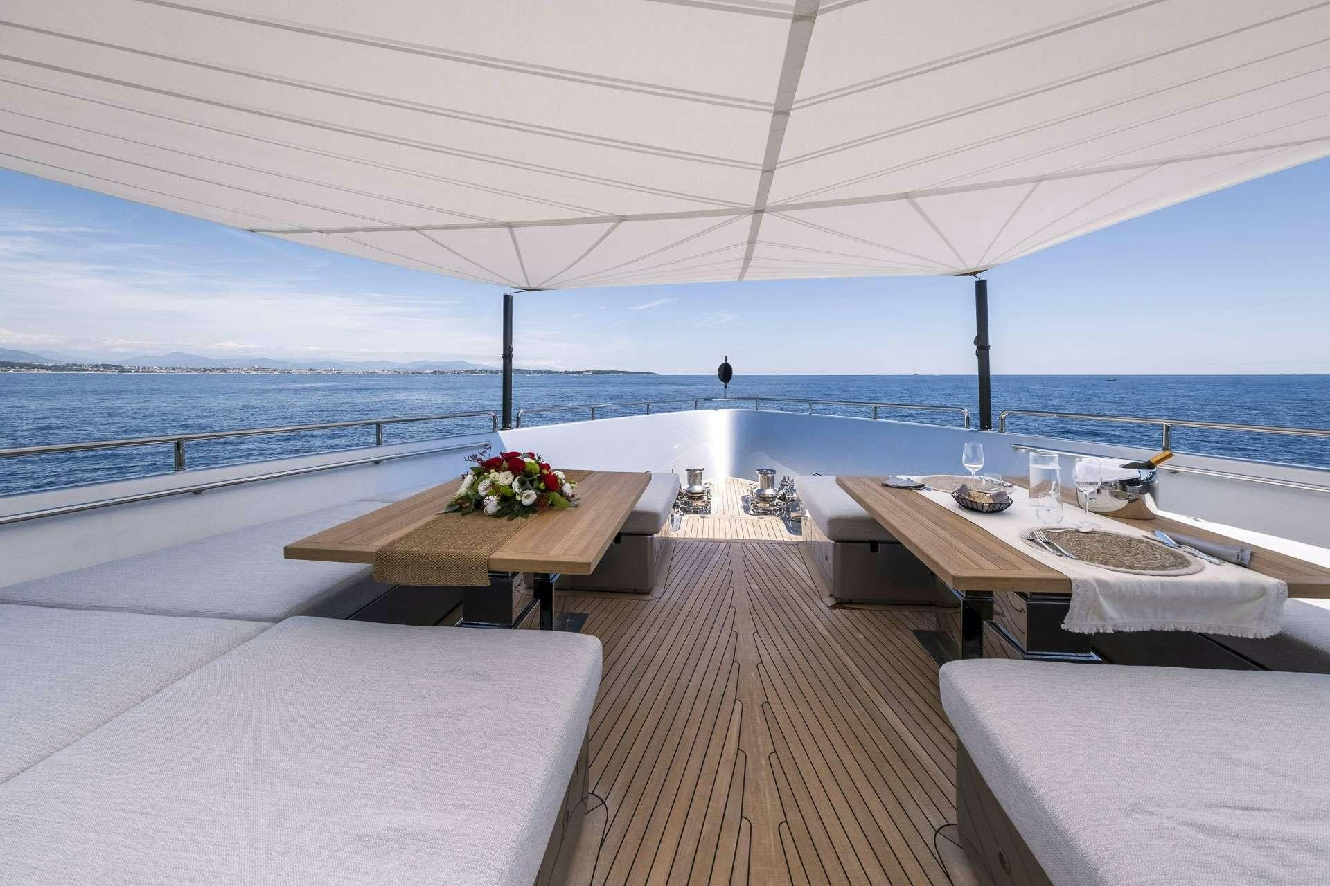 a room with a table and chairs on it and a body of water in the background aboard SENSA Yacht for Charter