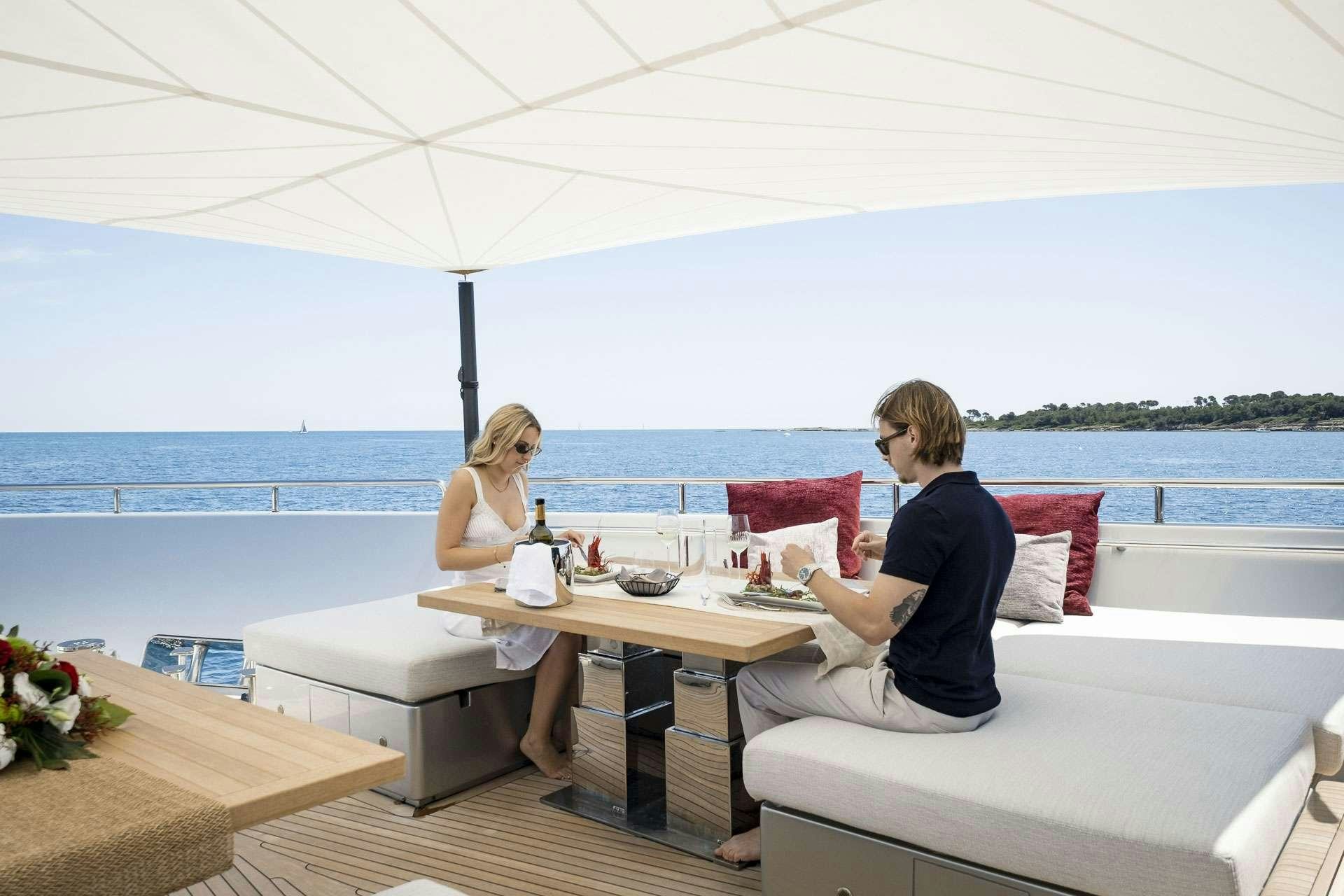 a couple of people sitting on a couch outside by a table aboard SENSA Yacht for Charter