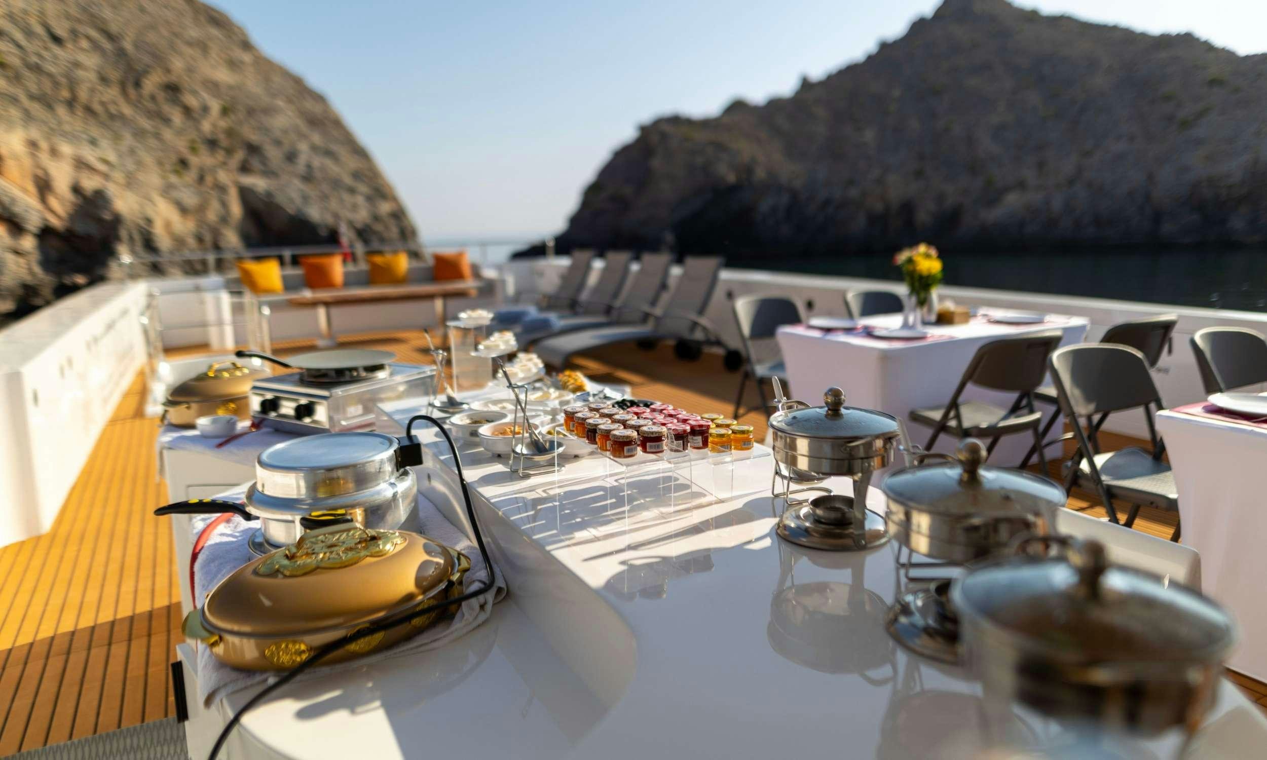 a table with chairs and a large waterfall in the background aboard VISION Yacht for Charter