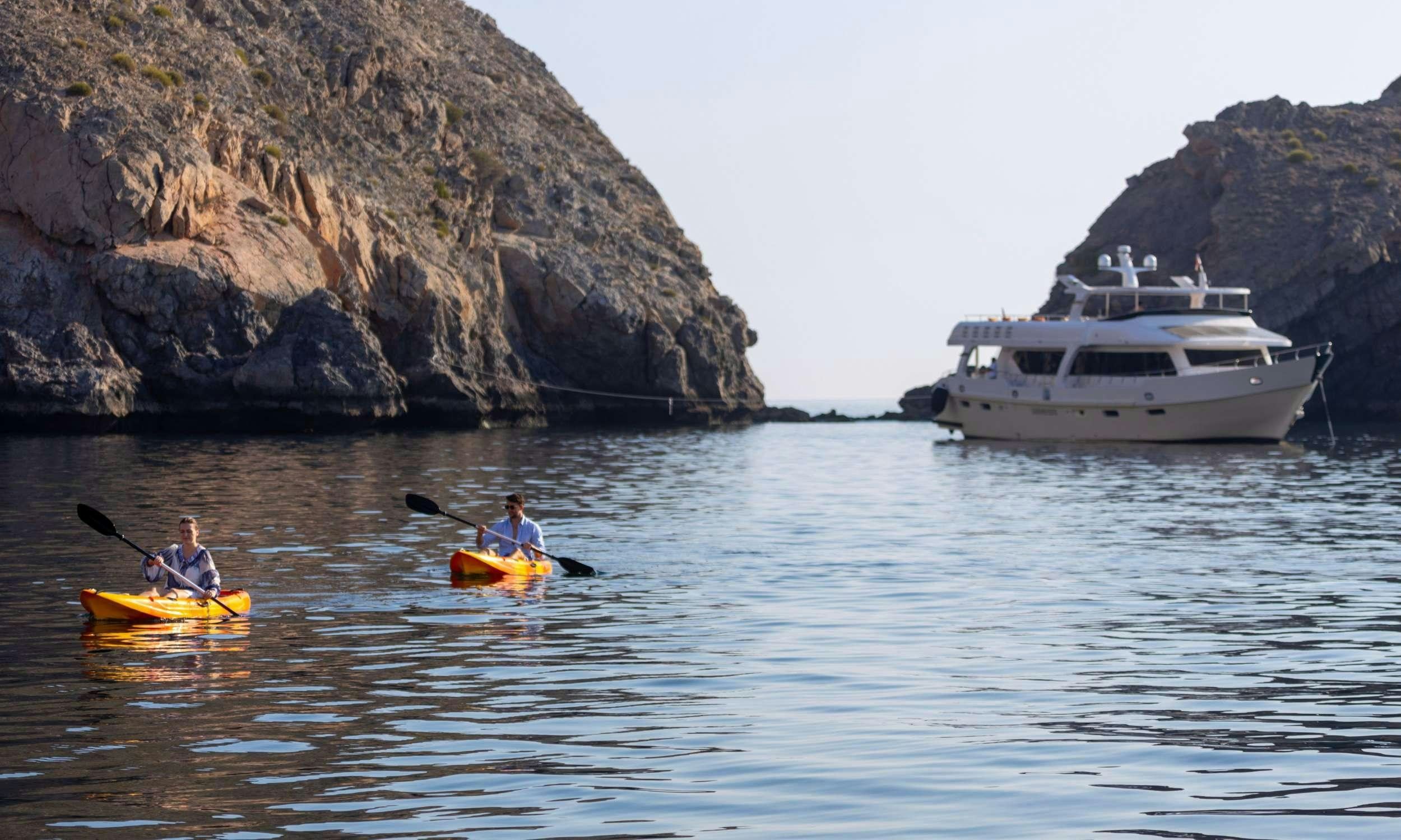 a man and a woman in a kayak in a lake aboard VISION Yacht for Charter