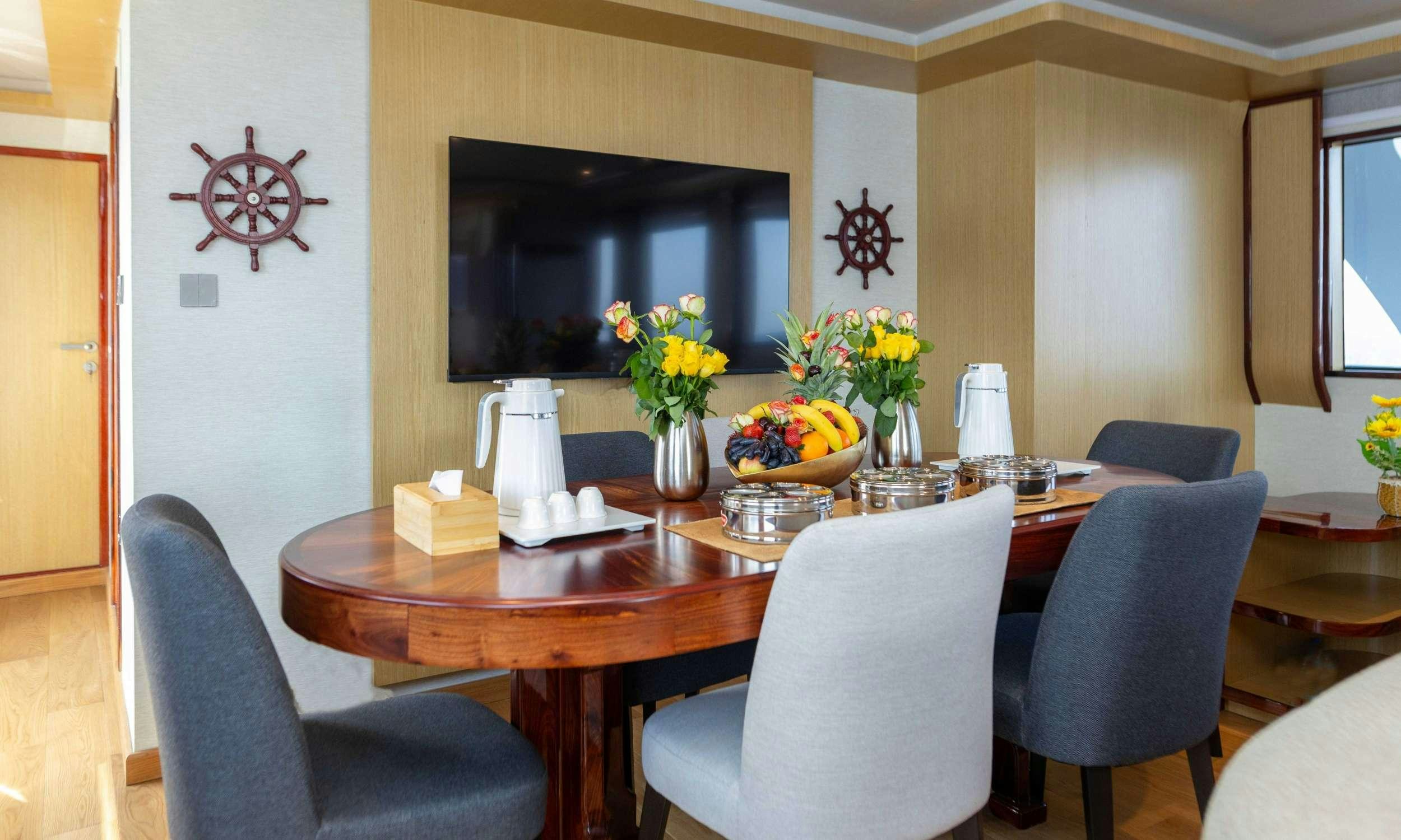 a dining table with chairs and a vase of flowers on it aboard VISION Yacht for Charter