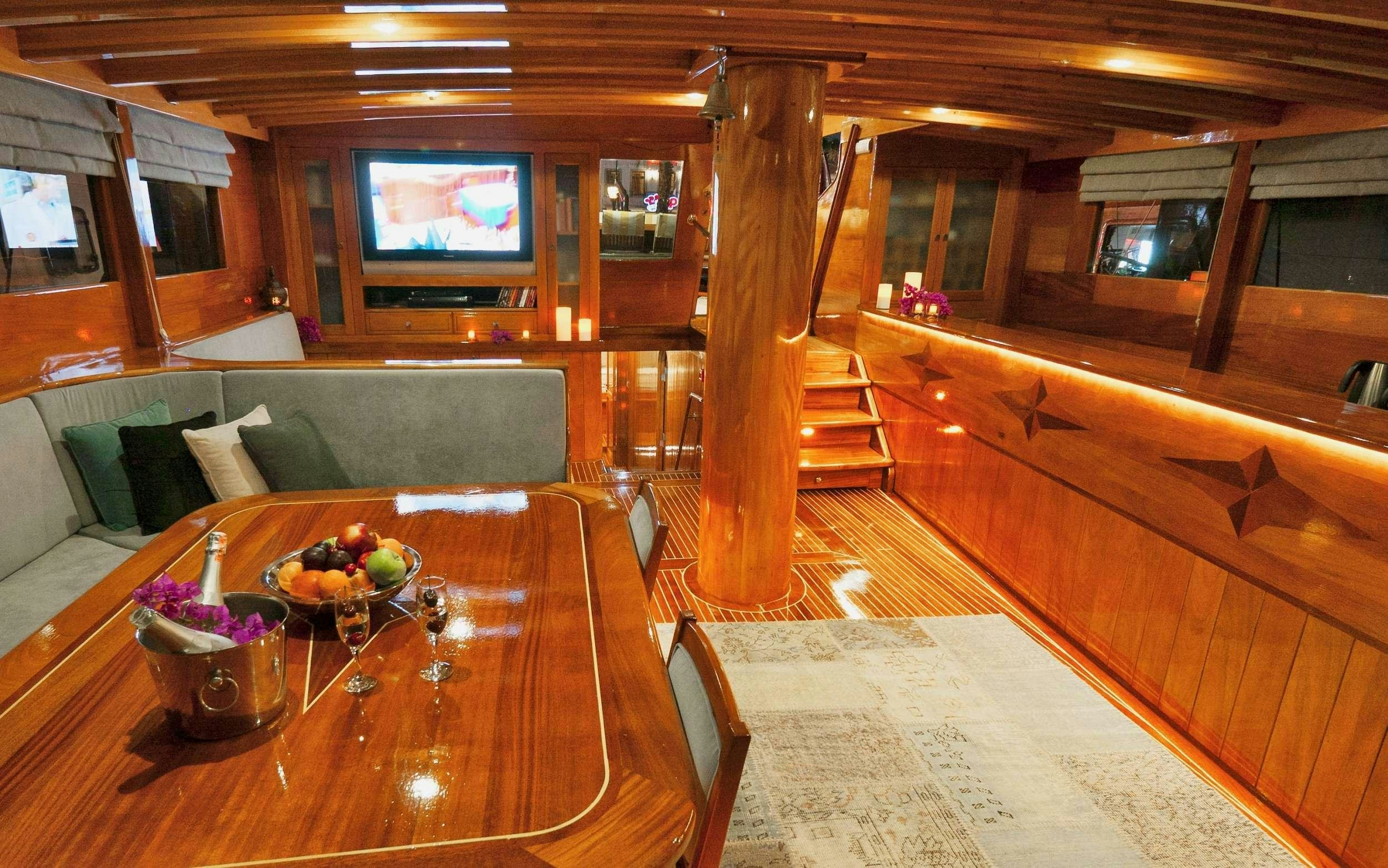 a living room with a wood table and a tv aboard PARSS Yacht for Charter