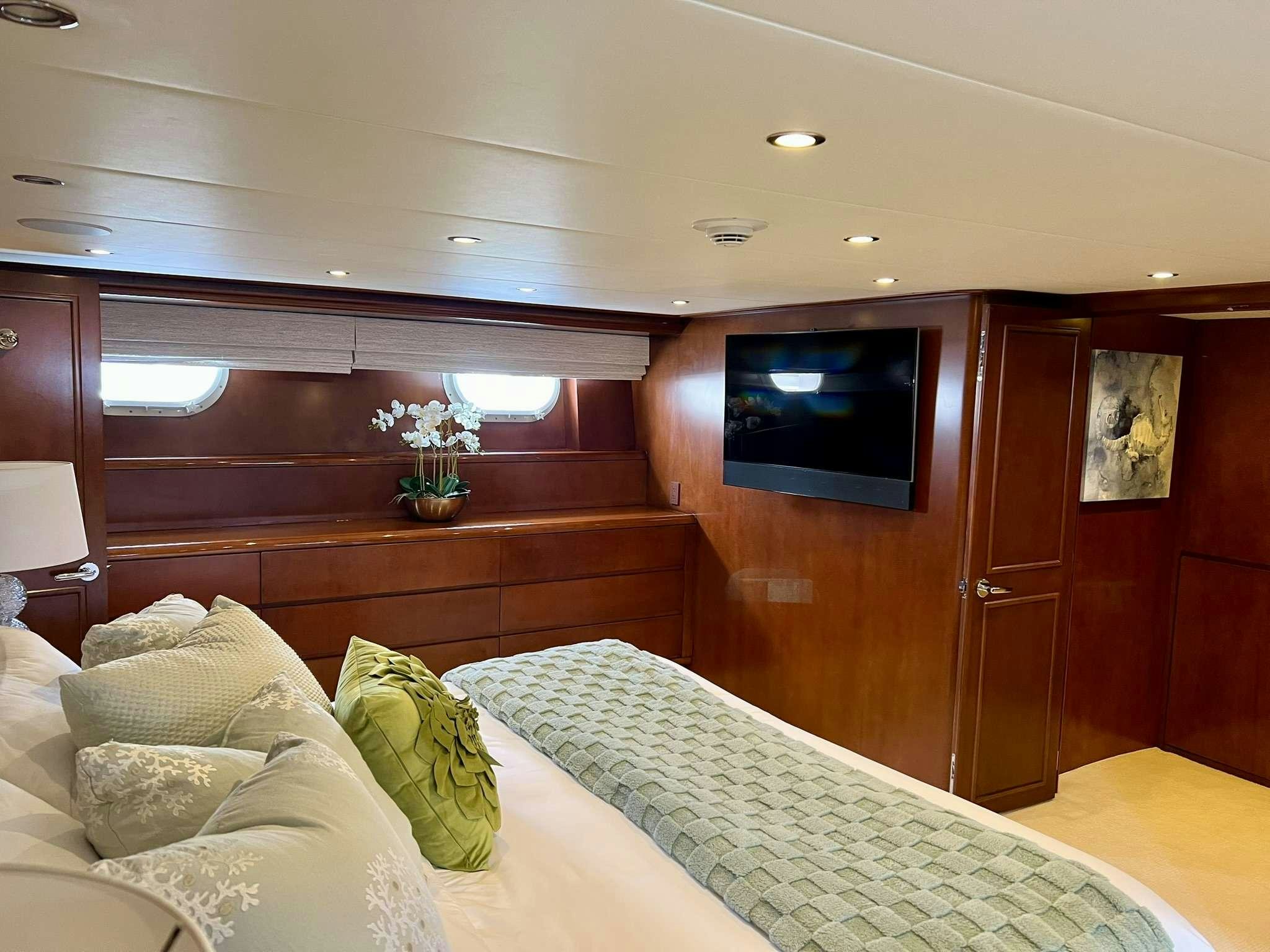 a room with a bed and a television on the wall aboard ESCAPE Yacht for Charter