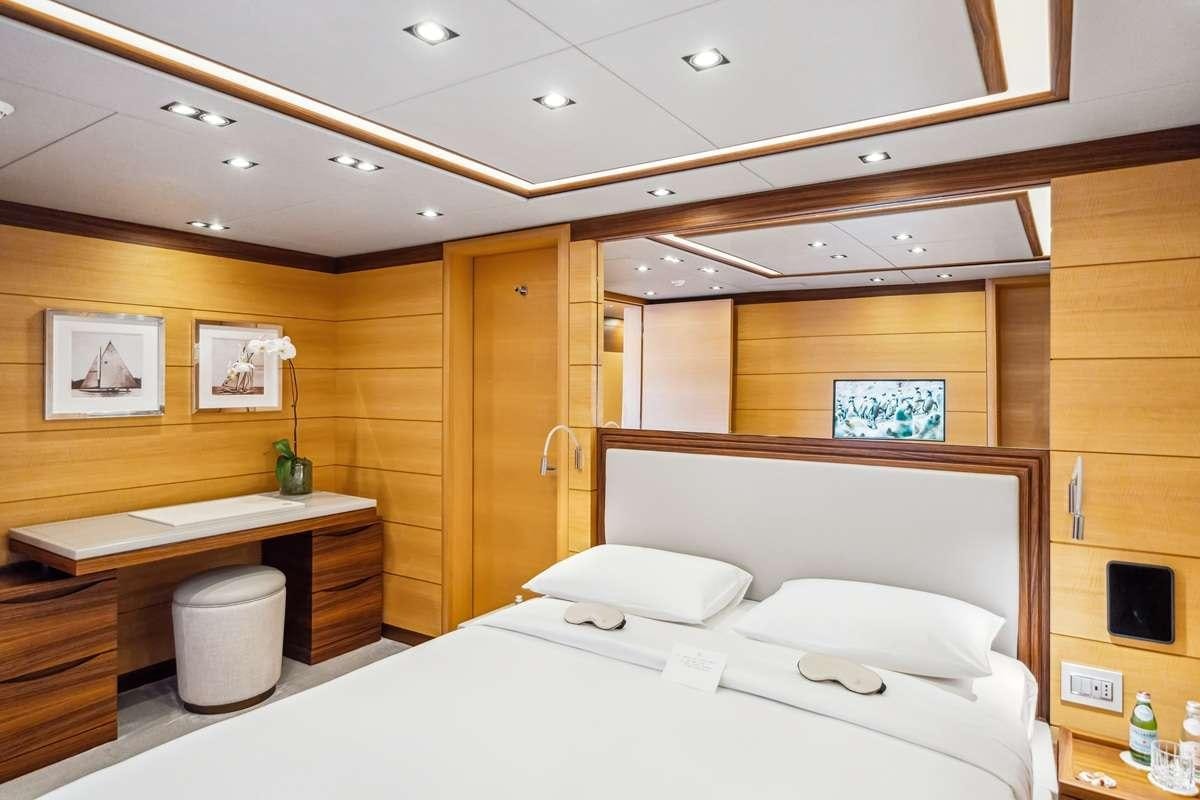 a room with a bed and desk aboard BOMBAY Yacht for Charter
