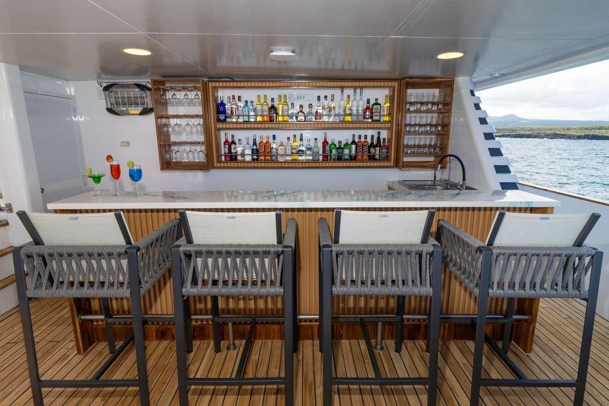 a bar with a bar and a group of chairs aboard GALAPAGOS ANGEL Yacht for Charter