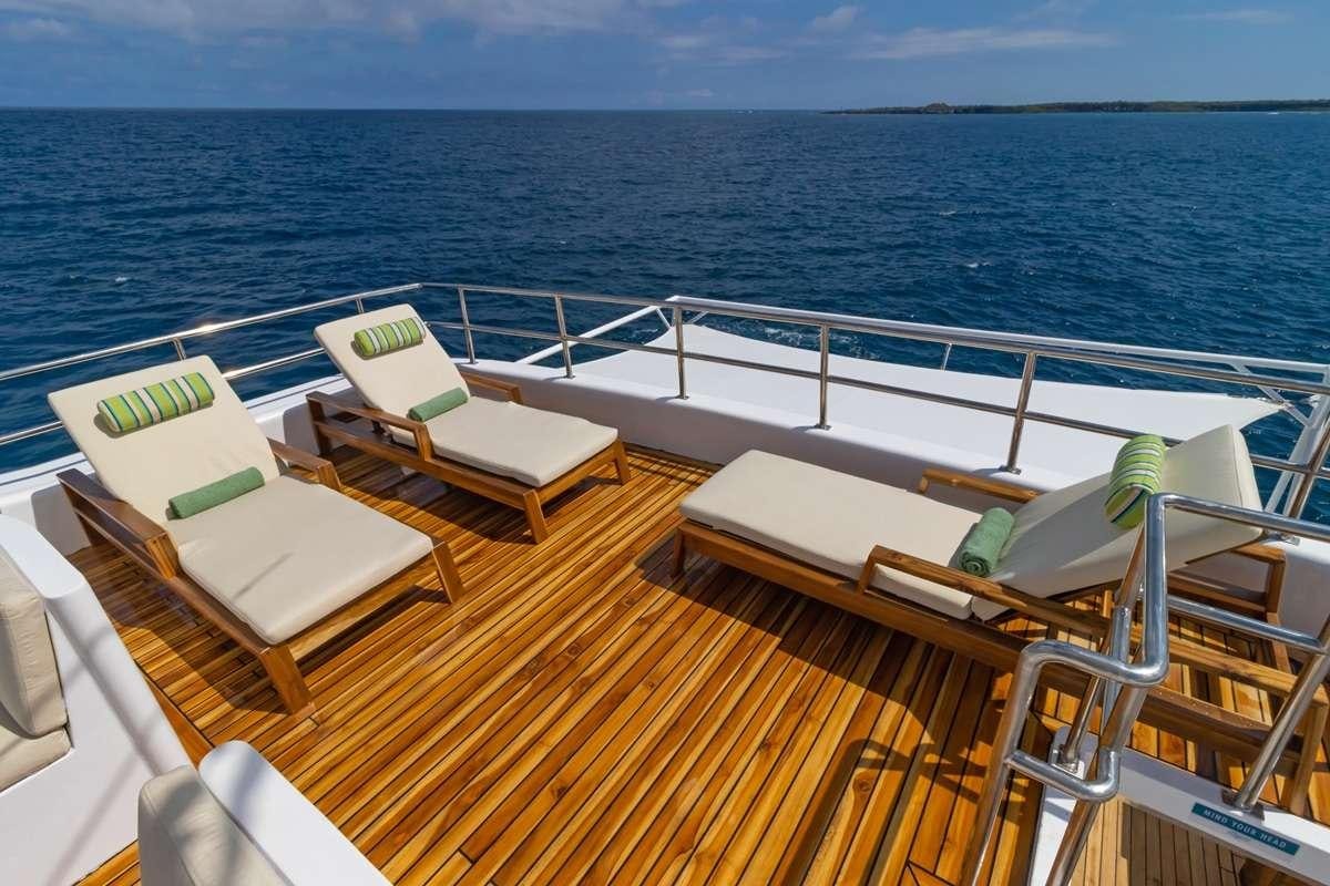 a deck with chairs and a body of water in the background aboard GALAPAGOS ANGEL Yacht for Charter