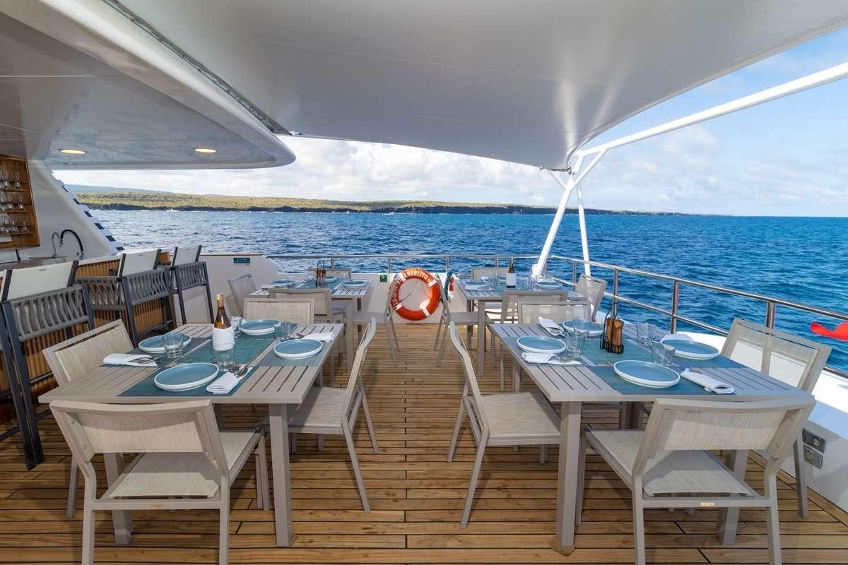 a patio with tables and chairs aboard GALAPAGOS ANGEL Yacht for Charter