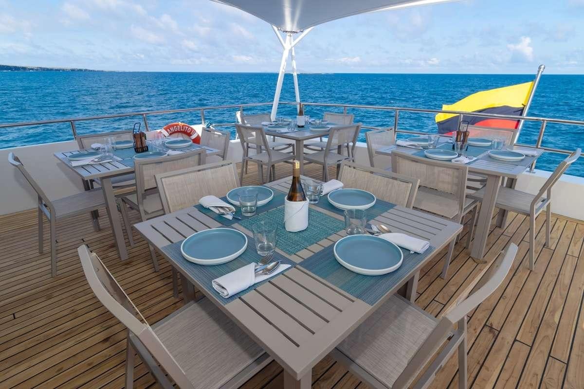 a table set for a meal on a deck overlooking the ocean aboard GALAPAGOS ANGEL Yacht for Charter