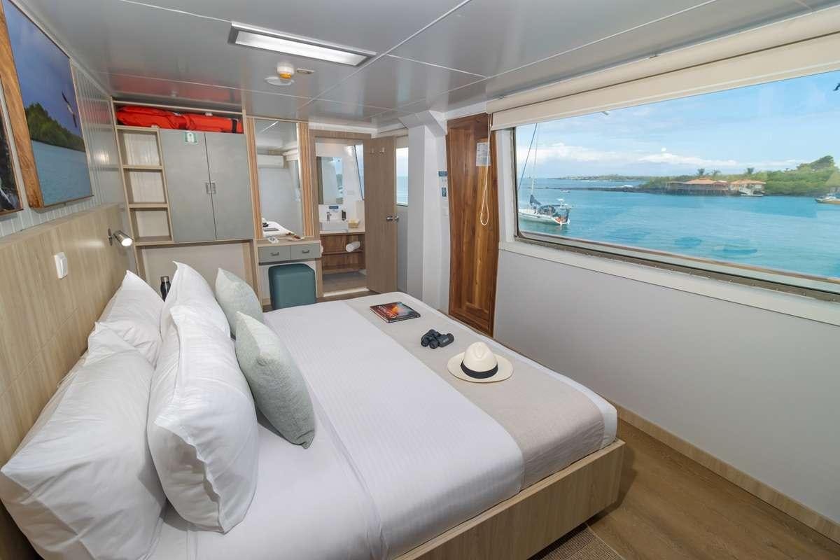 a room with a bed and a window aboard GALAPAGOS ANGEL Yacht for Charter