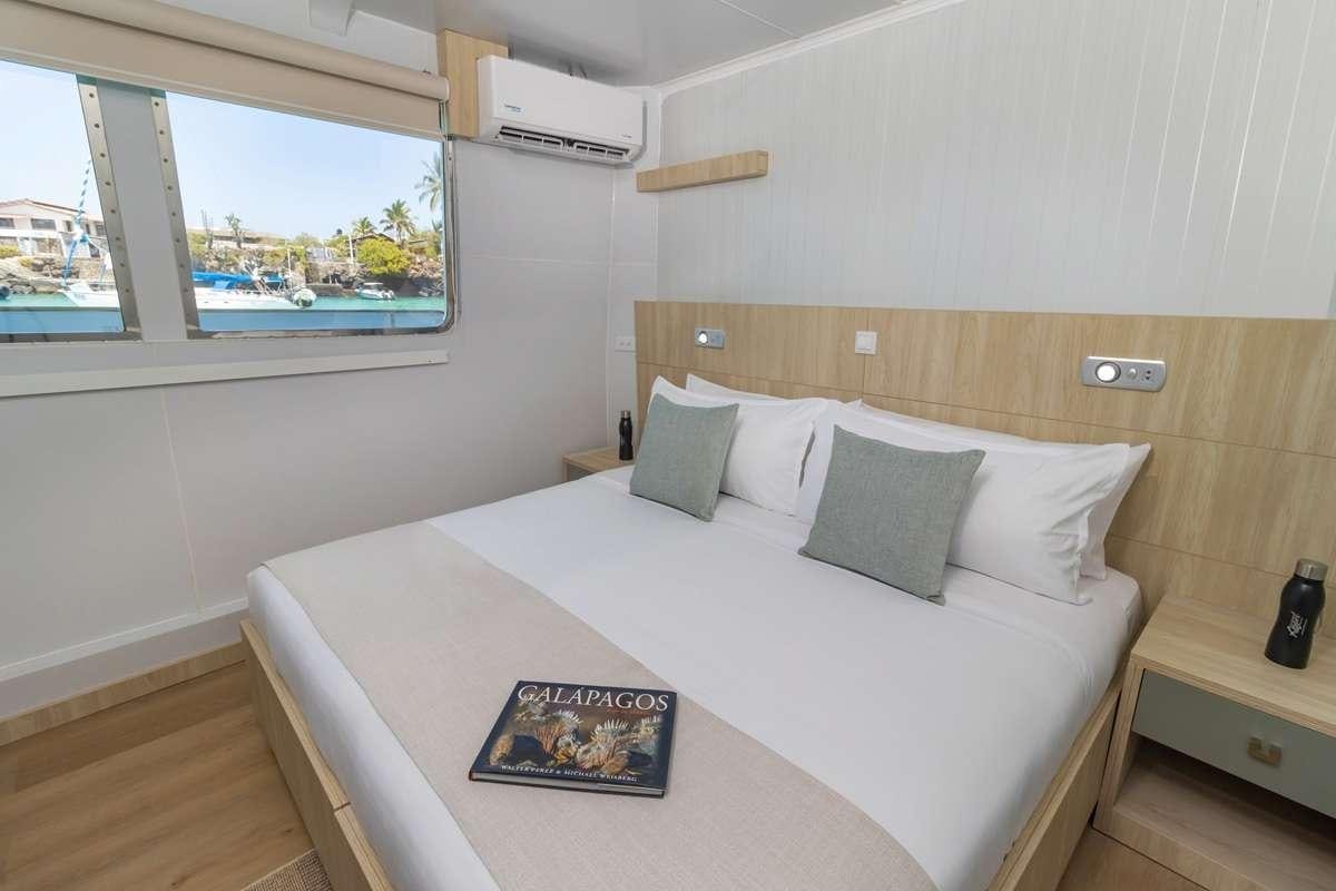 a bed with a white sheet and pillows on it aboard GALAPAGOS ANGEL Yacht for Charter