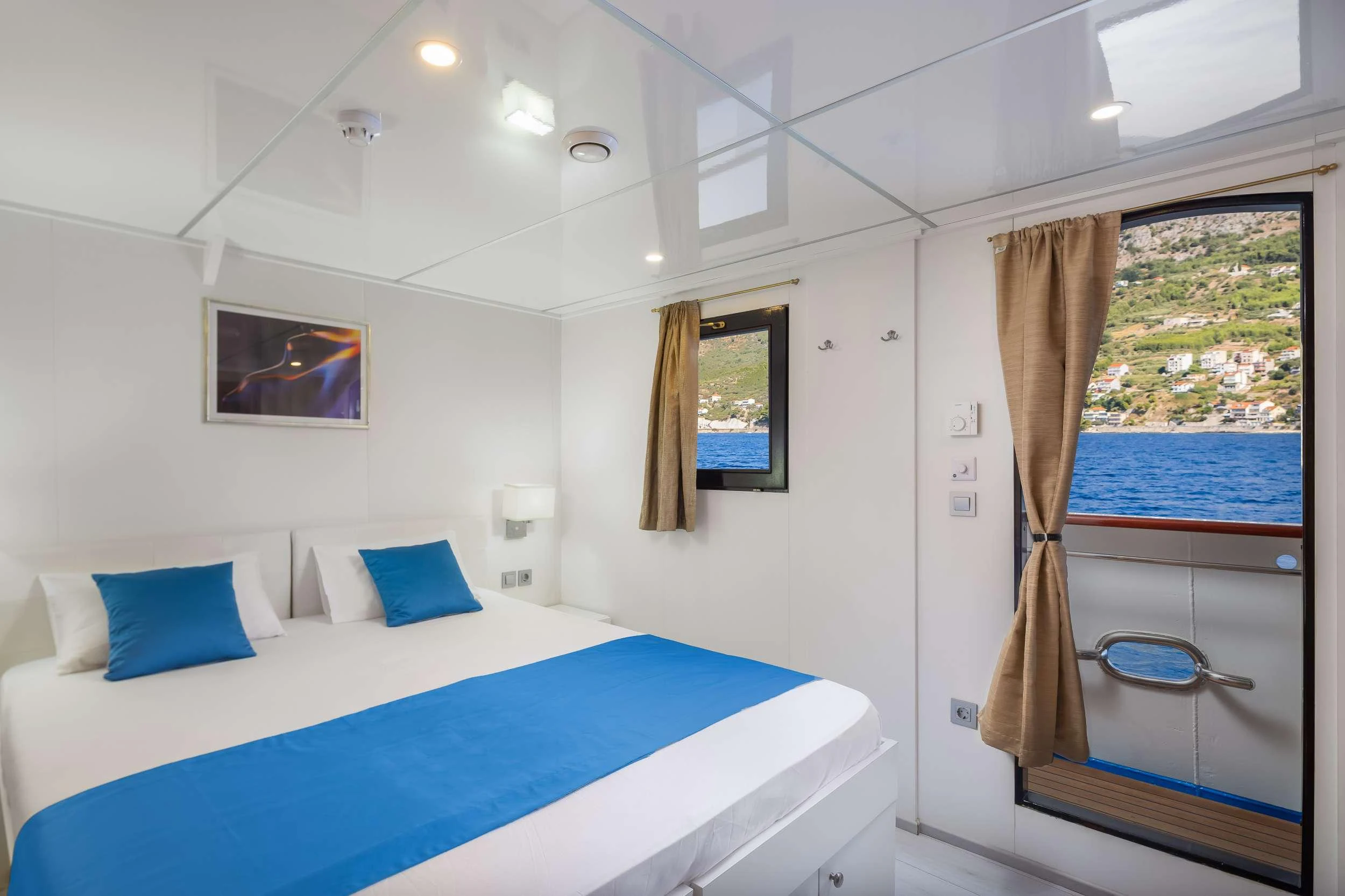 a bedroom with a bed and a window aboard AMALIA Yacht for Charter