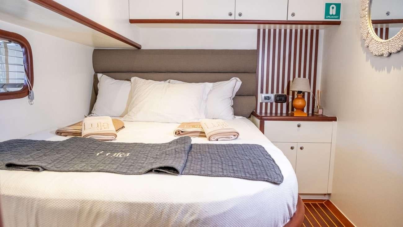 a bed with a blue and white blanket and a white dresser aboard LUJA Yacht for Charter
