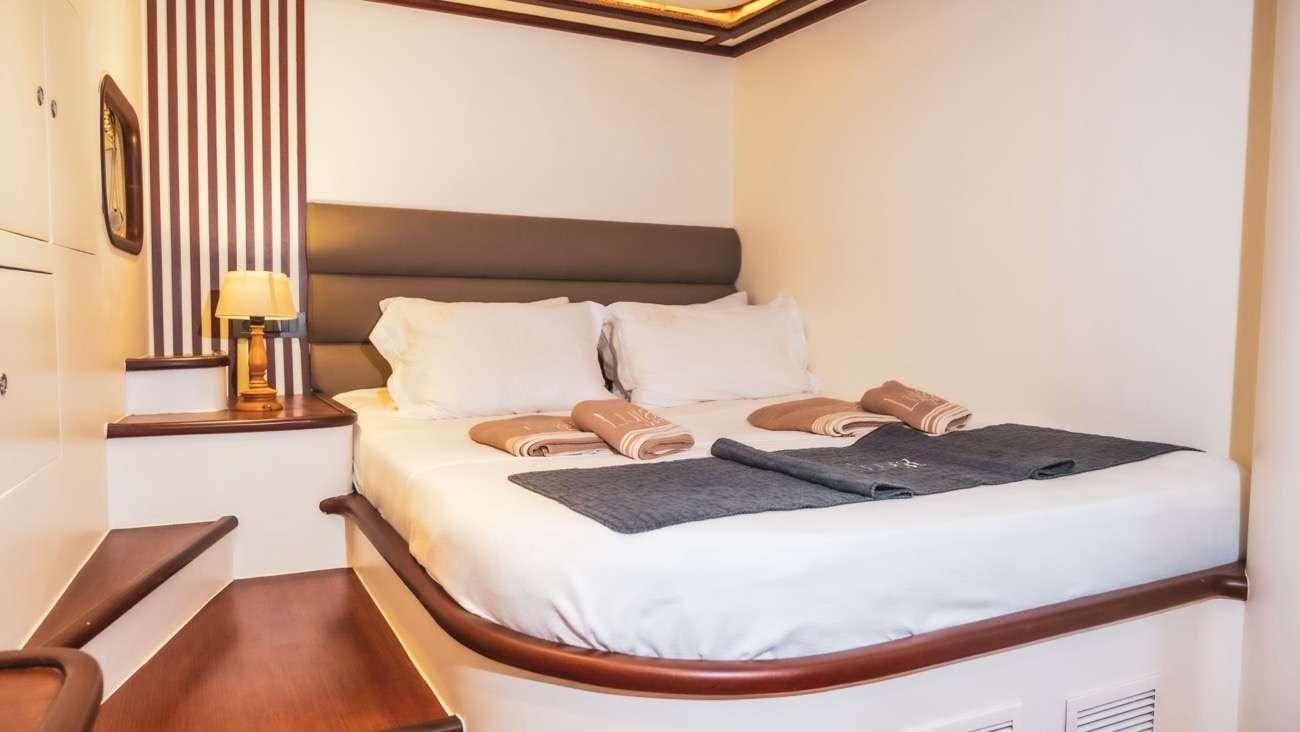 a bed with a blue blanket aboard LUJA Yacht for Charter