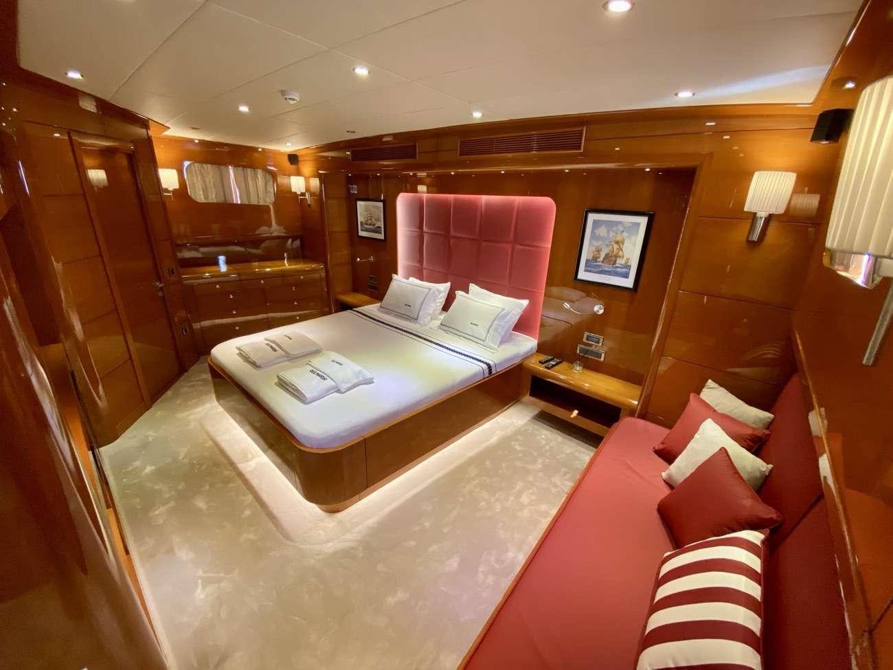 a hotel room with a bed and a red couch aboard CANARIA Yacht for Charter