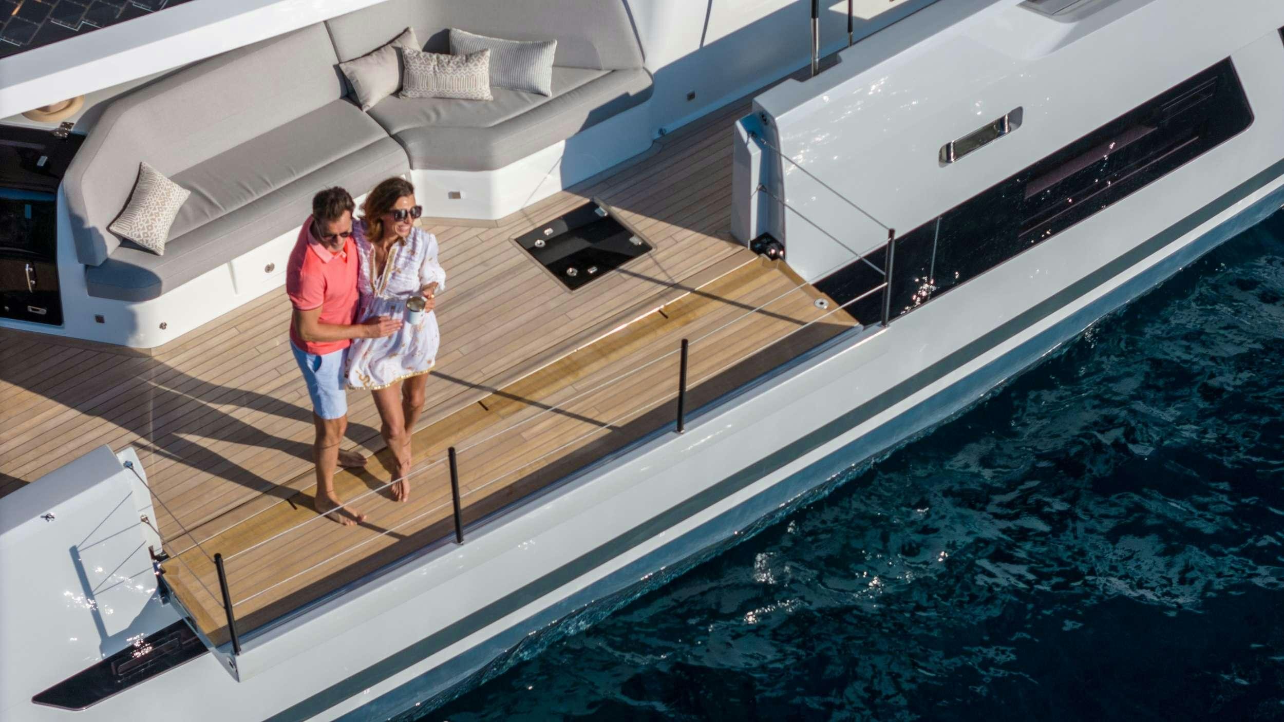 a couple of people standing on a deck of a boat aboard CHRISTAL MIO 80 Yacht for Charter