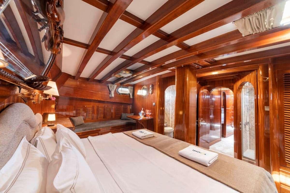 a room with a bed and a table aboard TORINI Yacht for Charter
