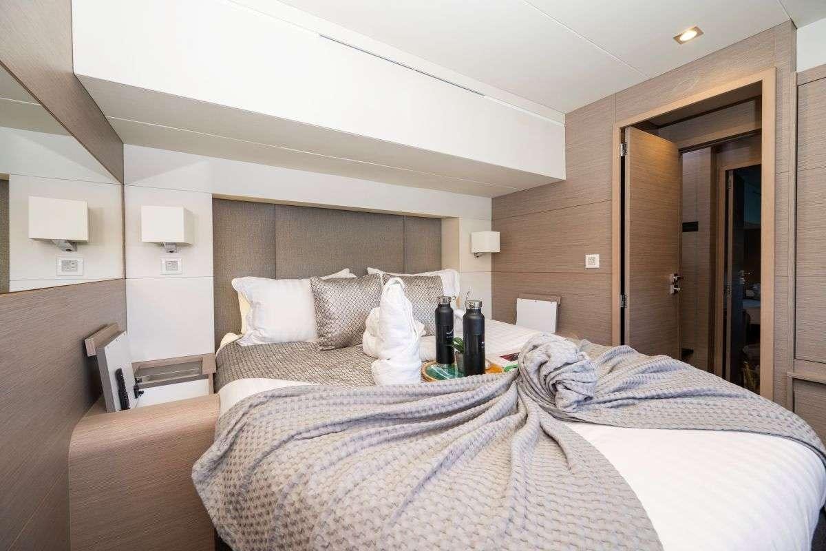 a hotel room with a bed and bottles on the table aboard LYRA Yacht for Charter