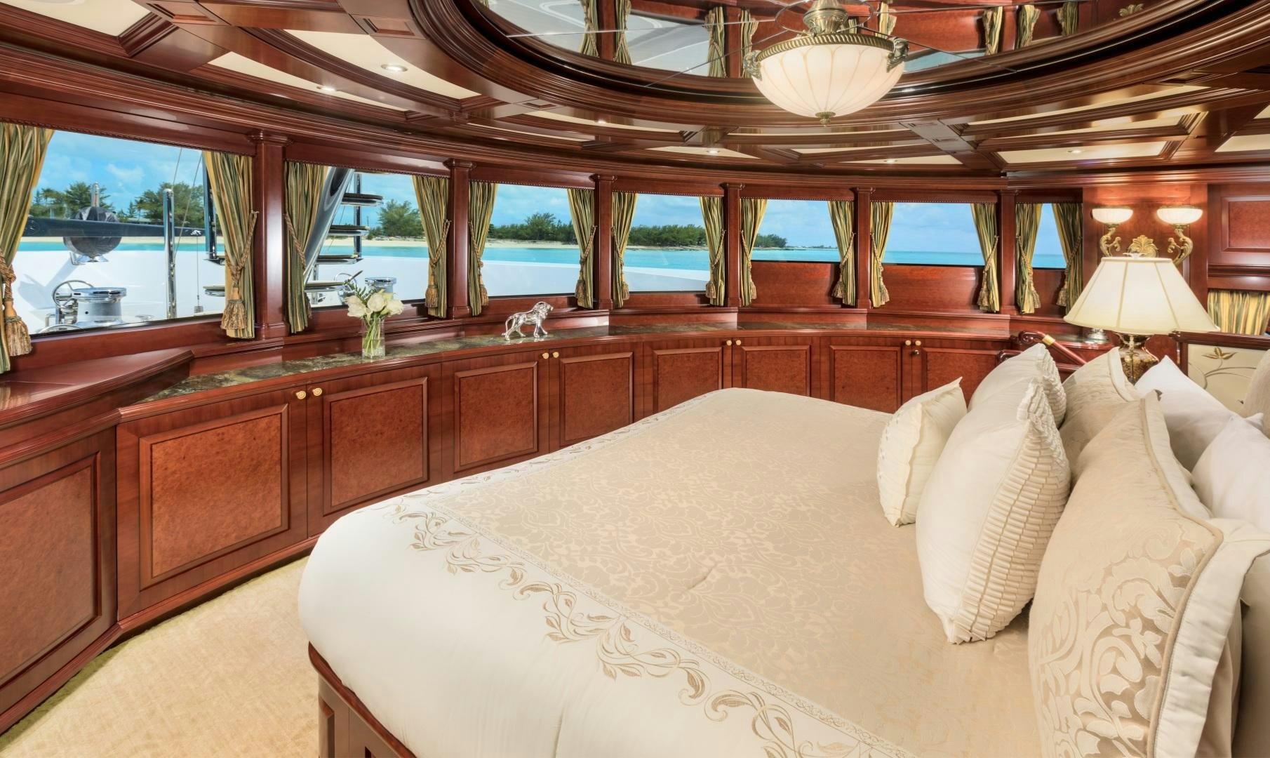 a bed with pillows and a chandelier above it aboard AMARULA SUN Yacht for Sale