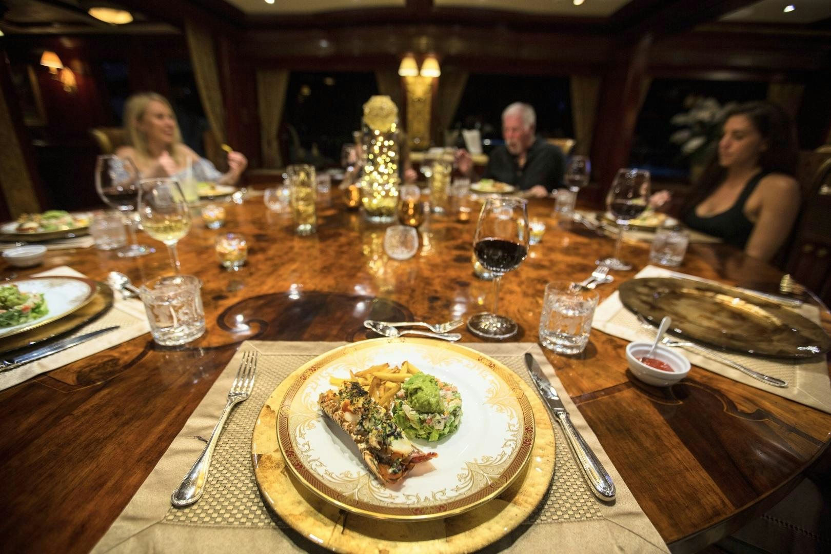 a table with plates and glasses of wine aboard AMARULA SUN Yacht for Sale