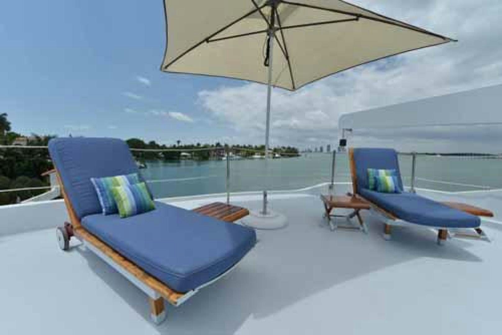 a couple of lounge chairs under an umbrella on a deck aboard UTOPIA III Yacht for Sale