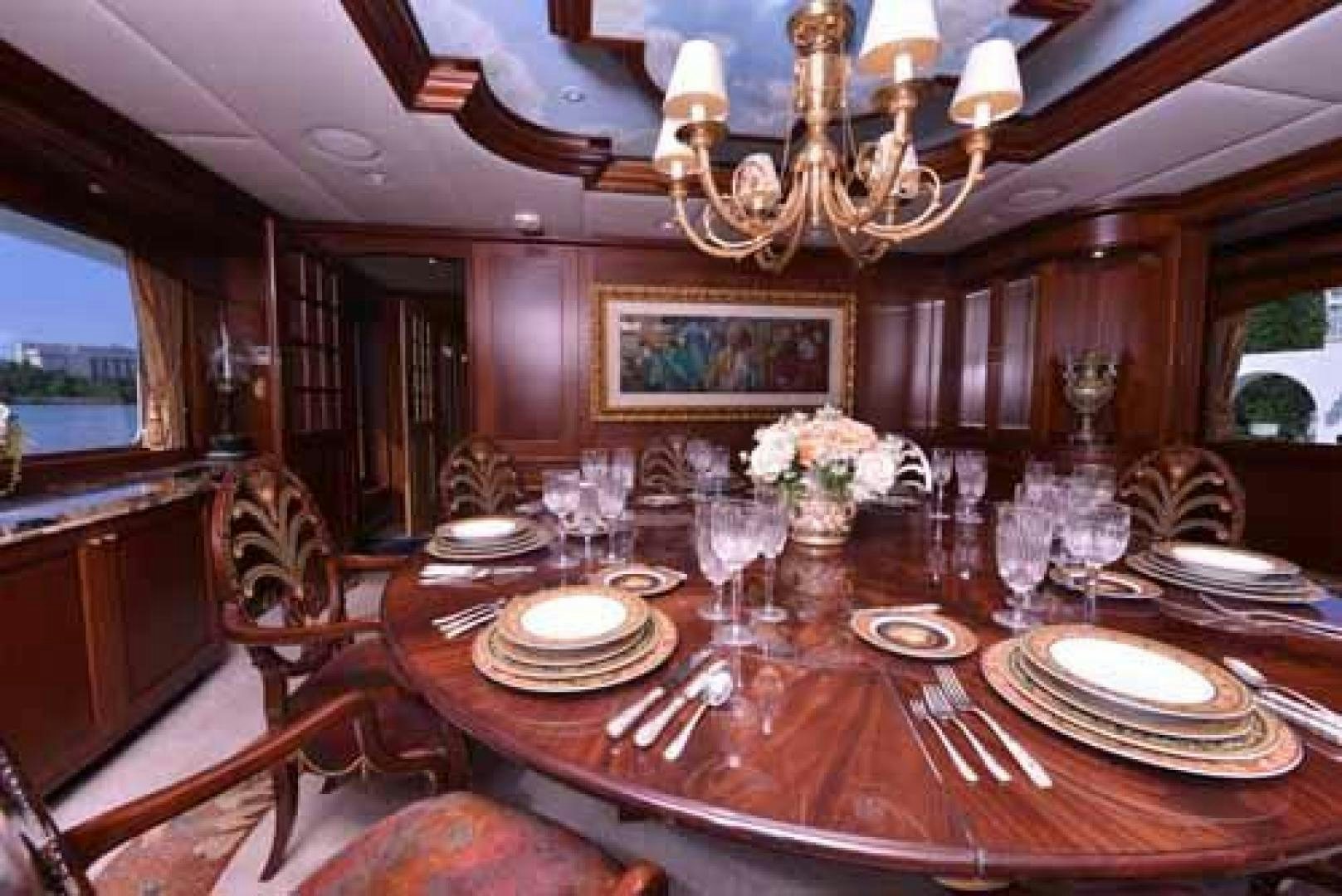 a dining room with a chandelier and a table set for a dinner aboard UTOPIA III Yacht for Sale