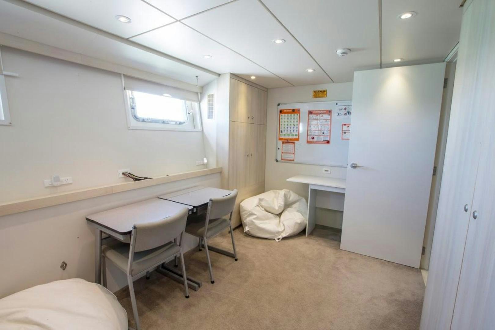 a room with desks and chairs aboard KAHU Yacht for Sale