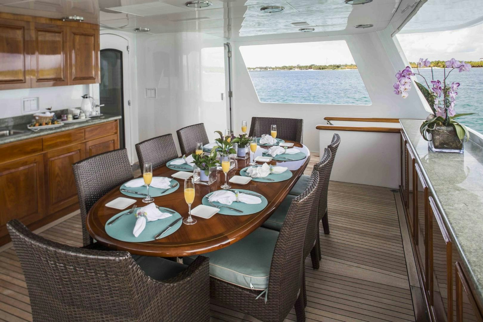 a dining table with chairs and a kitchen in the background aboard CHERISH Yacht for Sale