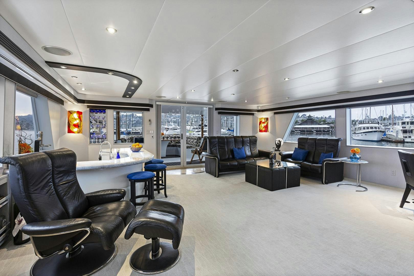 a living room with black leather couches and a large window aboard ISABELLA Yacht for Sale