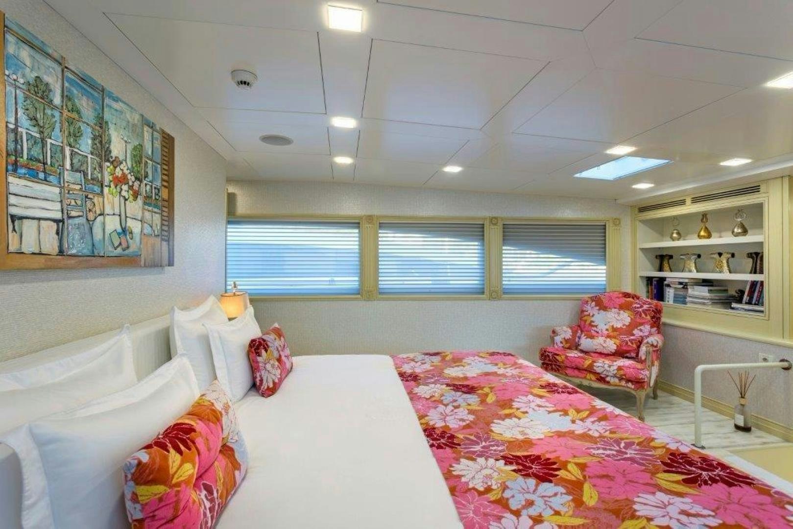 a bedroom with a bed and a chair aboard M&M Yacht for Sale