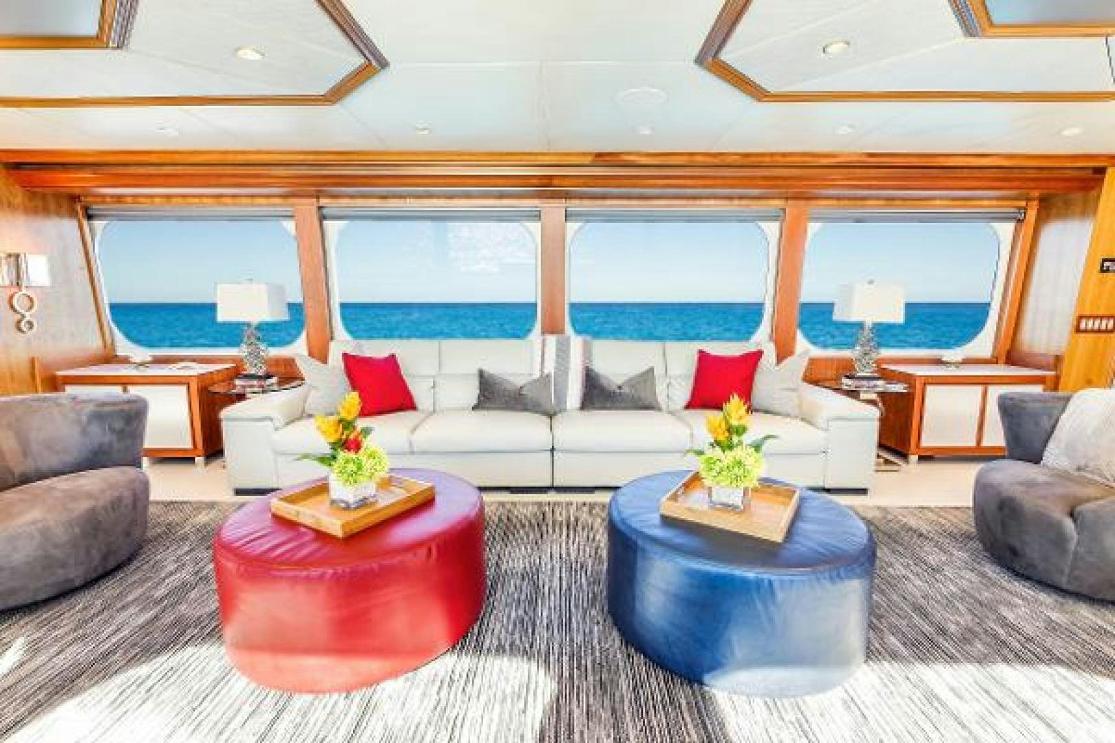 a living room with a large blue couch and a large window aboard IL CAPO Yacht for Sale