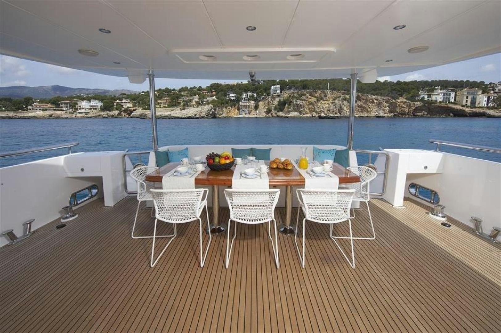 a table set for a meal on a deck overlooking a large body of water aboard JOHNSON 110 FLYBRIDGE Yacht for Sale