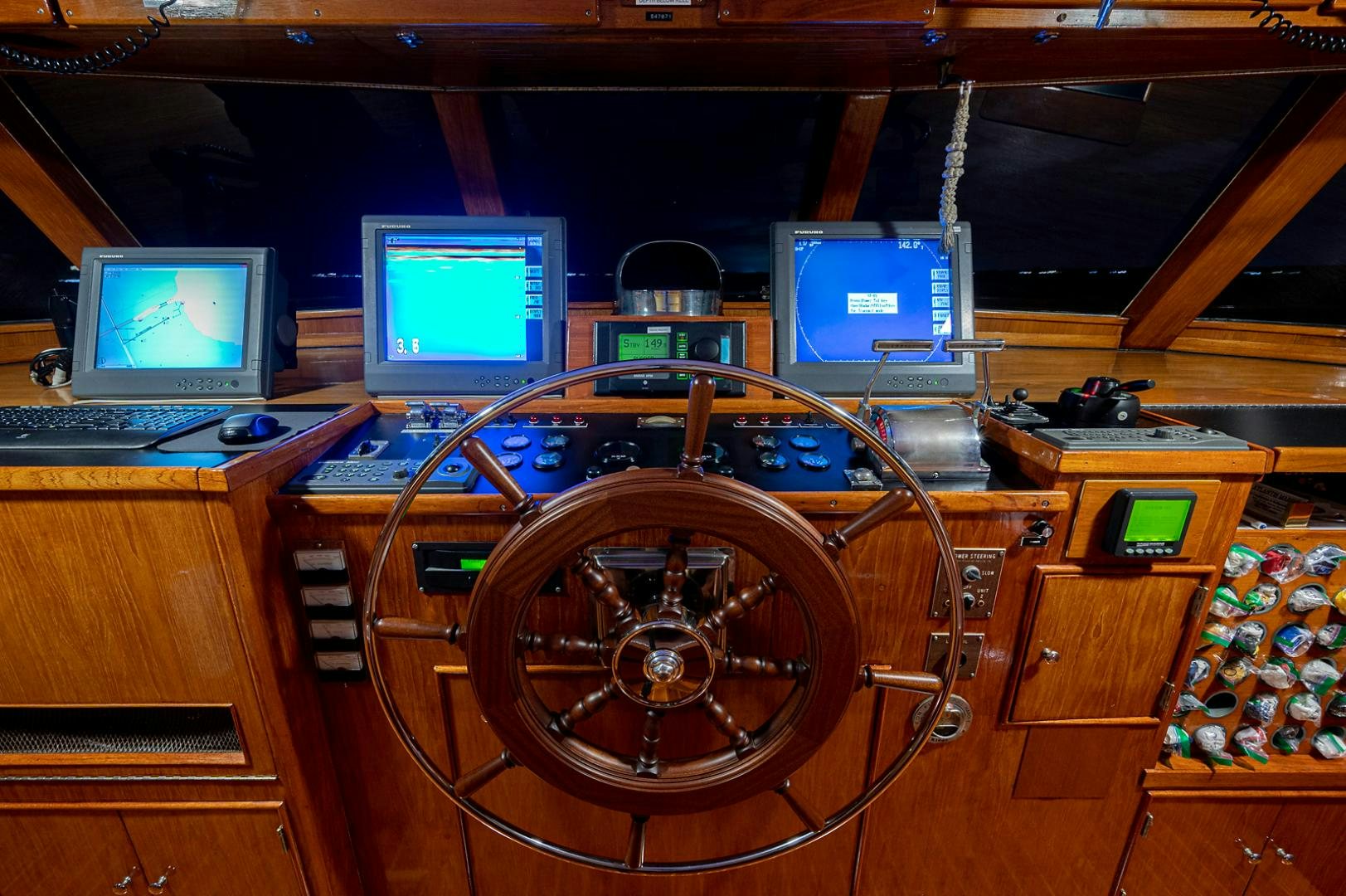 a wooden desk with a computer and a large round wheel aboard CHANTICLEER Yacht for Sale