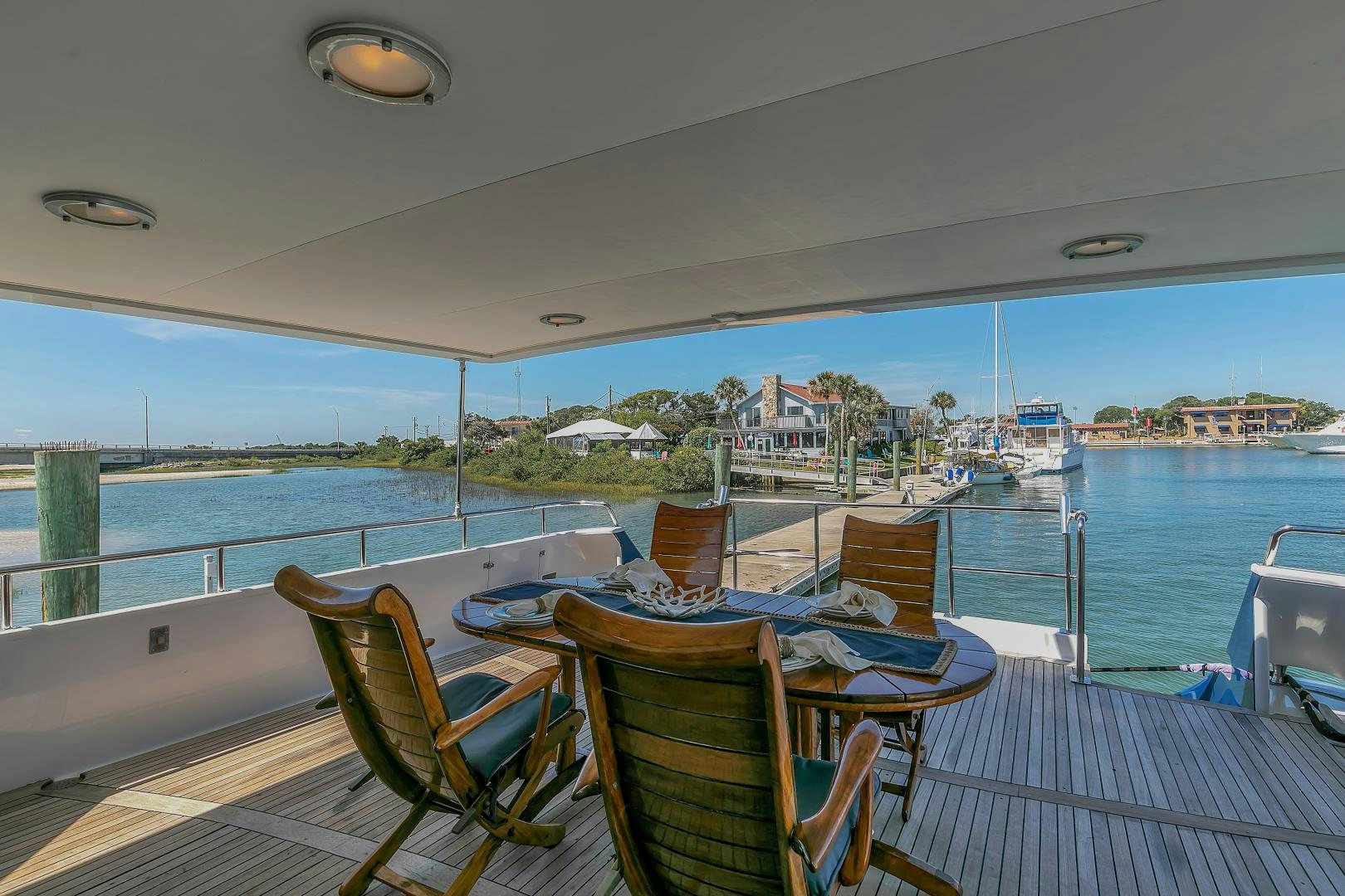 a deck with chairs and tables on it by a body of water aboard LA VIDA Yacht for Sale