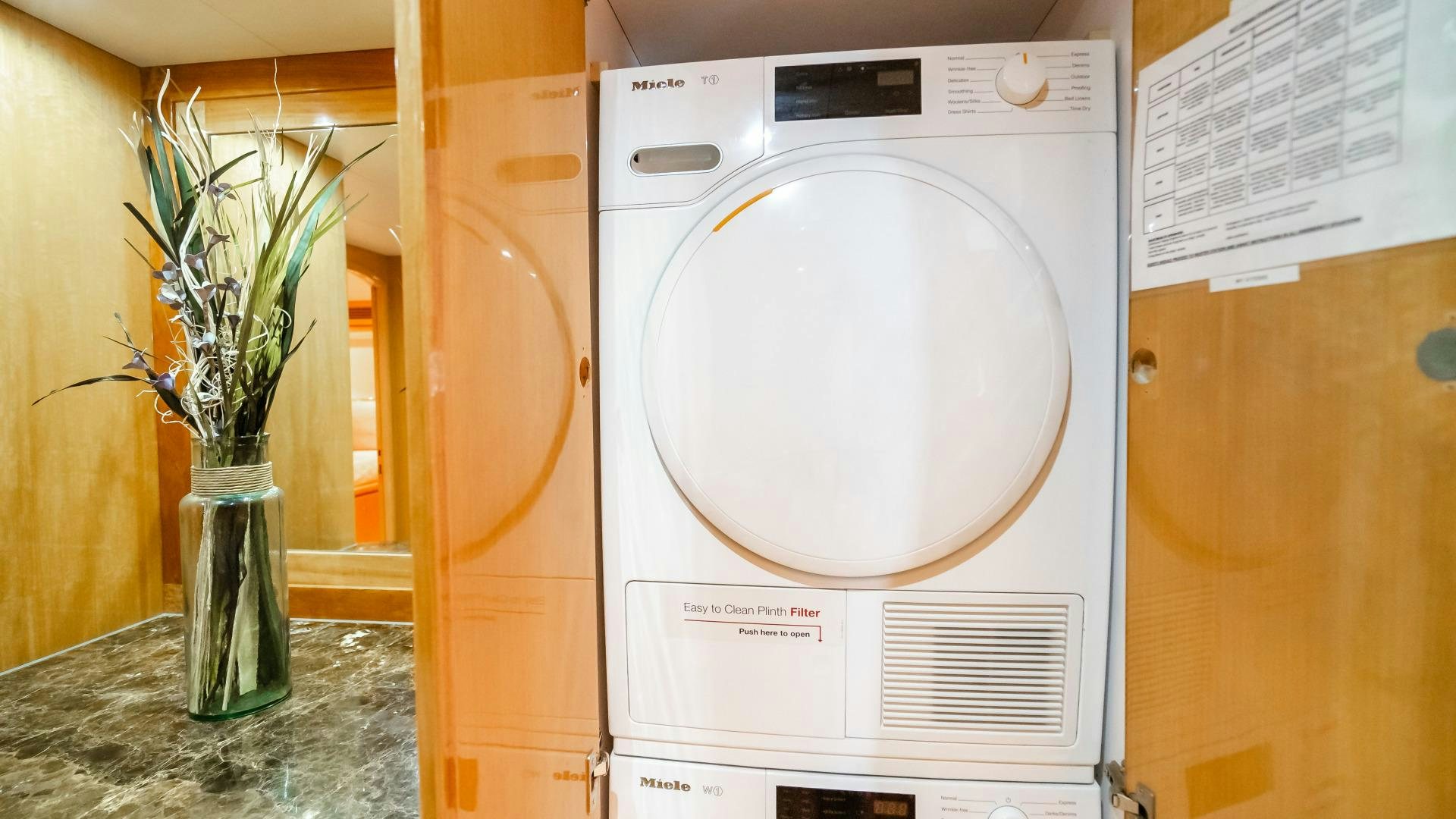 a white washing machine next to a vase with flowers aboard VITESSE Yacht for Sale
