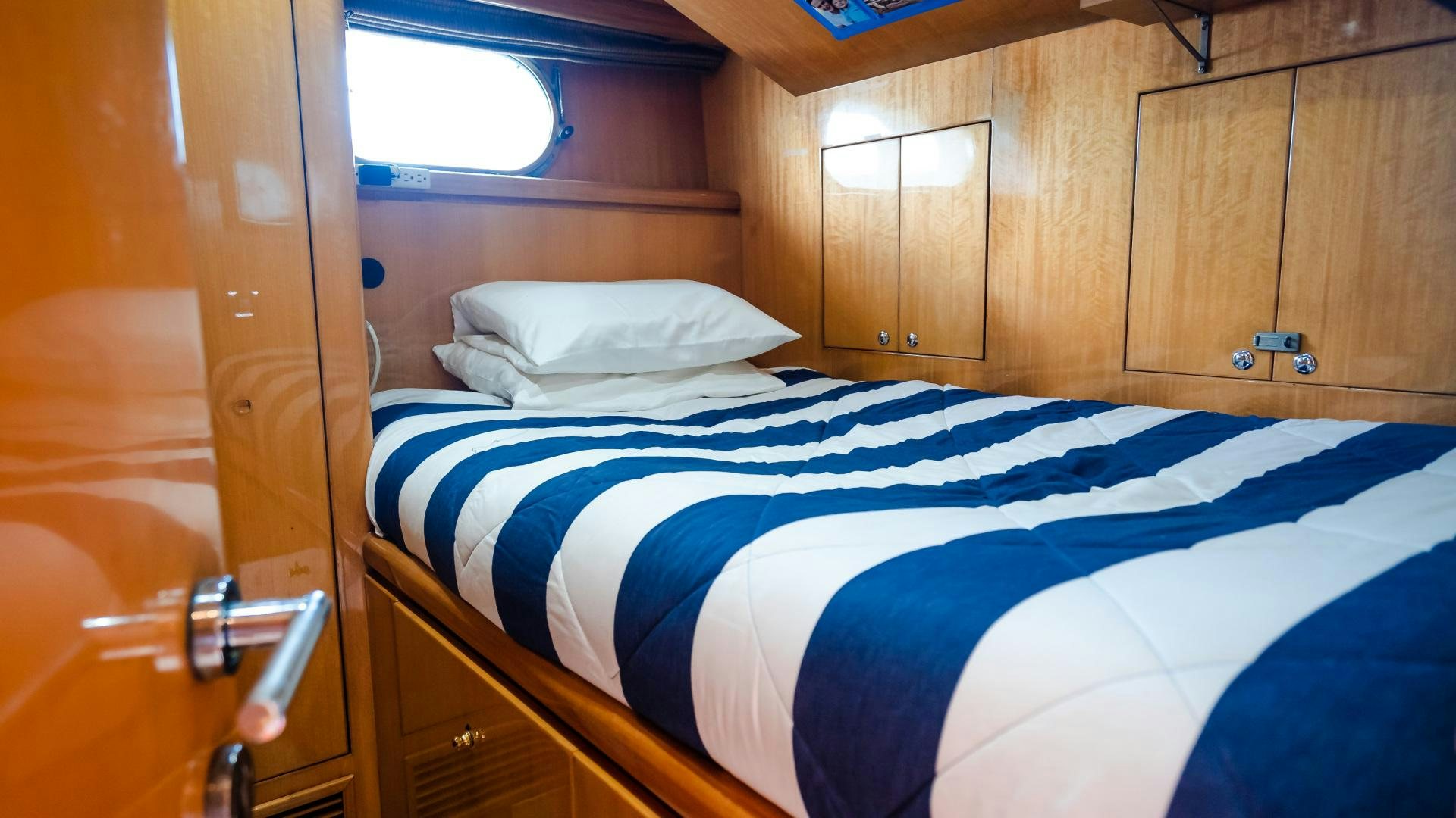 a bed with blue and white sheets aboard VITESSE Yacht for Sale