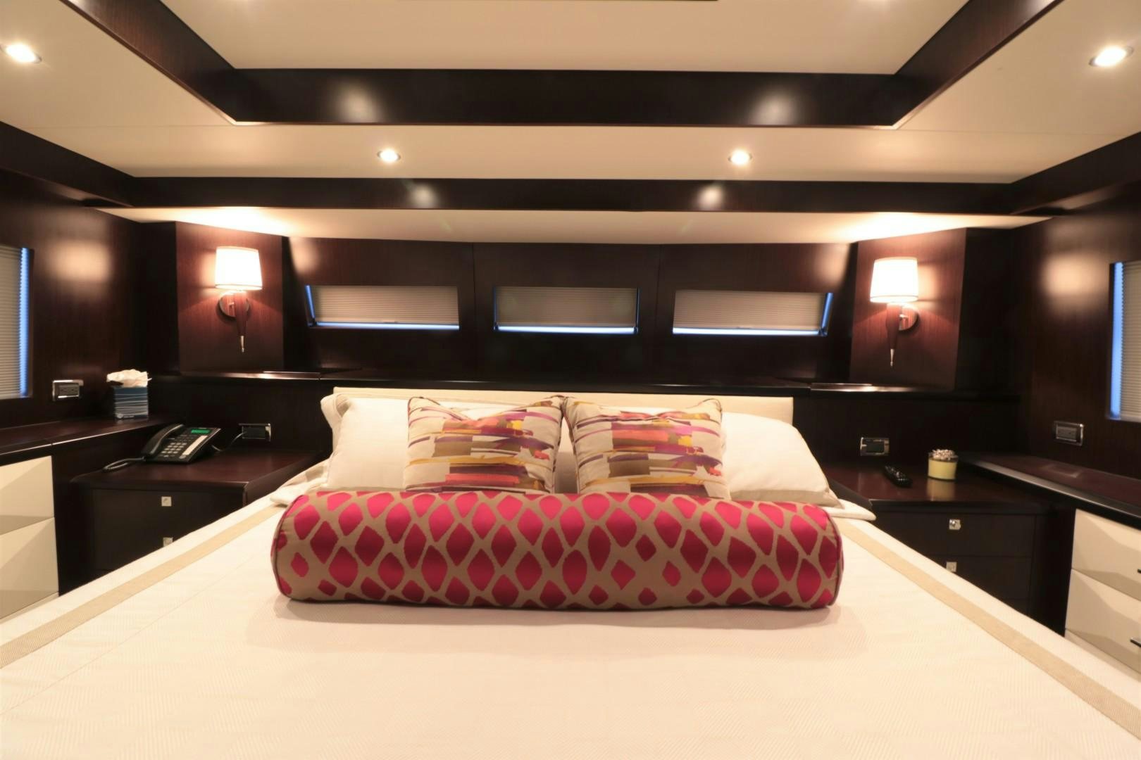 a bed with a red and white comforter in a room with a tv and a black wall aboard LADY CARMEN Yacht for Sale
