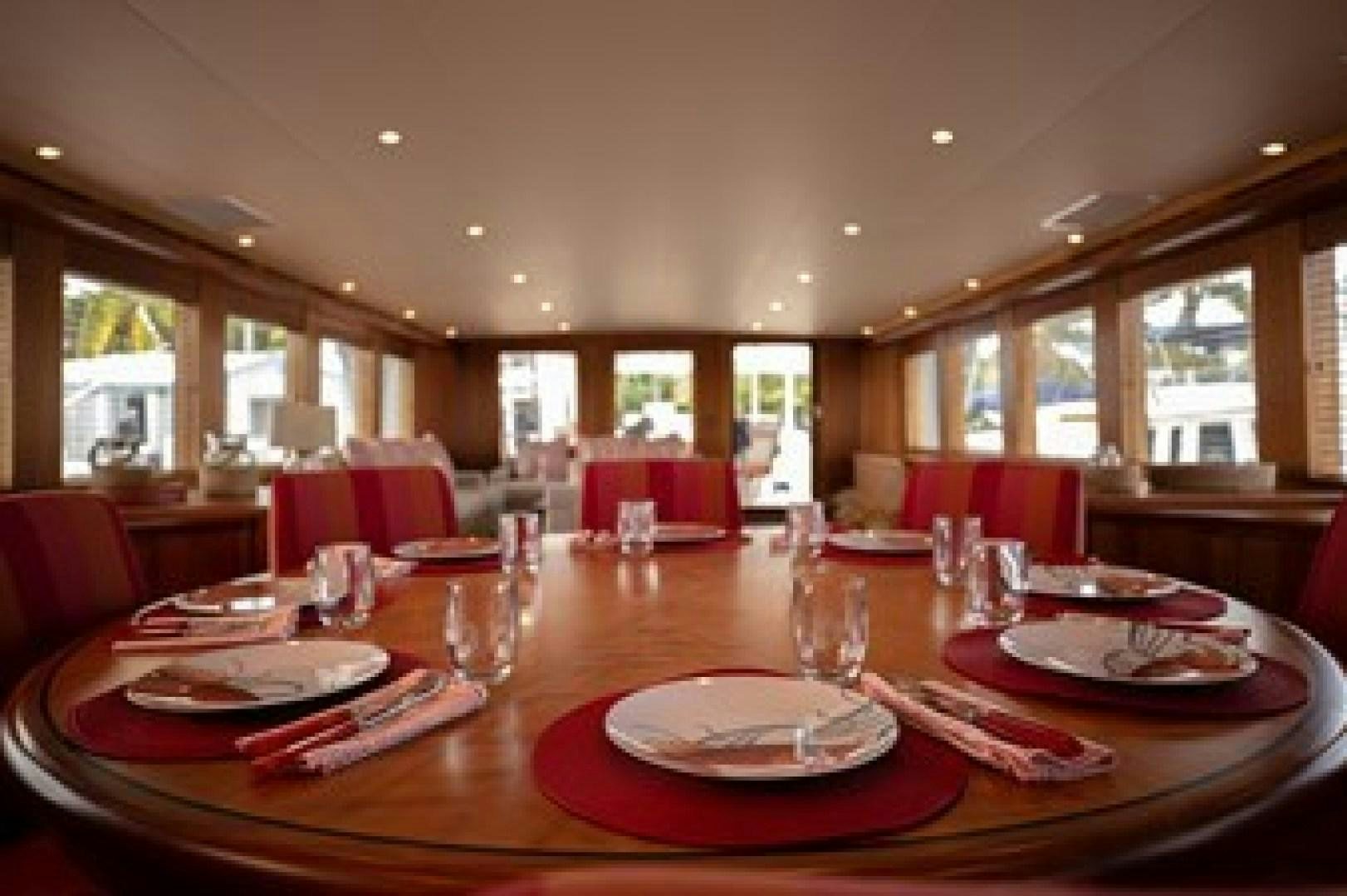 a dining room with red plates and chairs aboard TAIMA Yacht for Sale