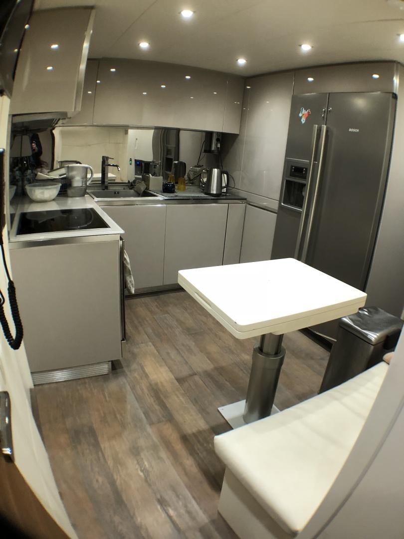 a kitchen with a table and refrigerator aboard DORIS Yacht for Sale