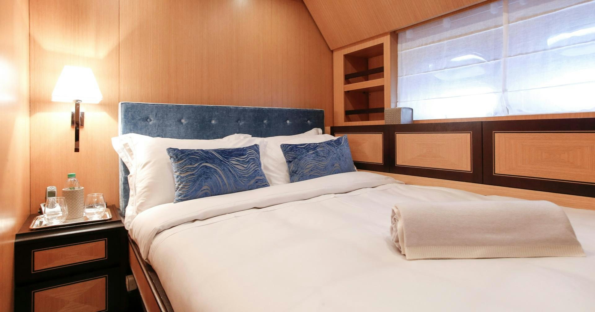 a bed with blue pillows aboard THE OFFICE Yacht for Sale