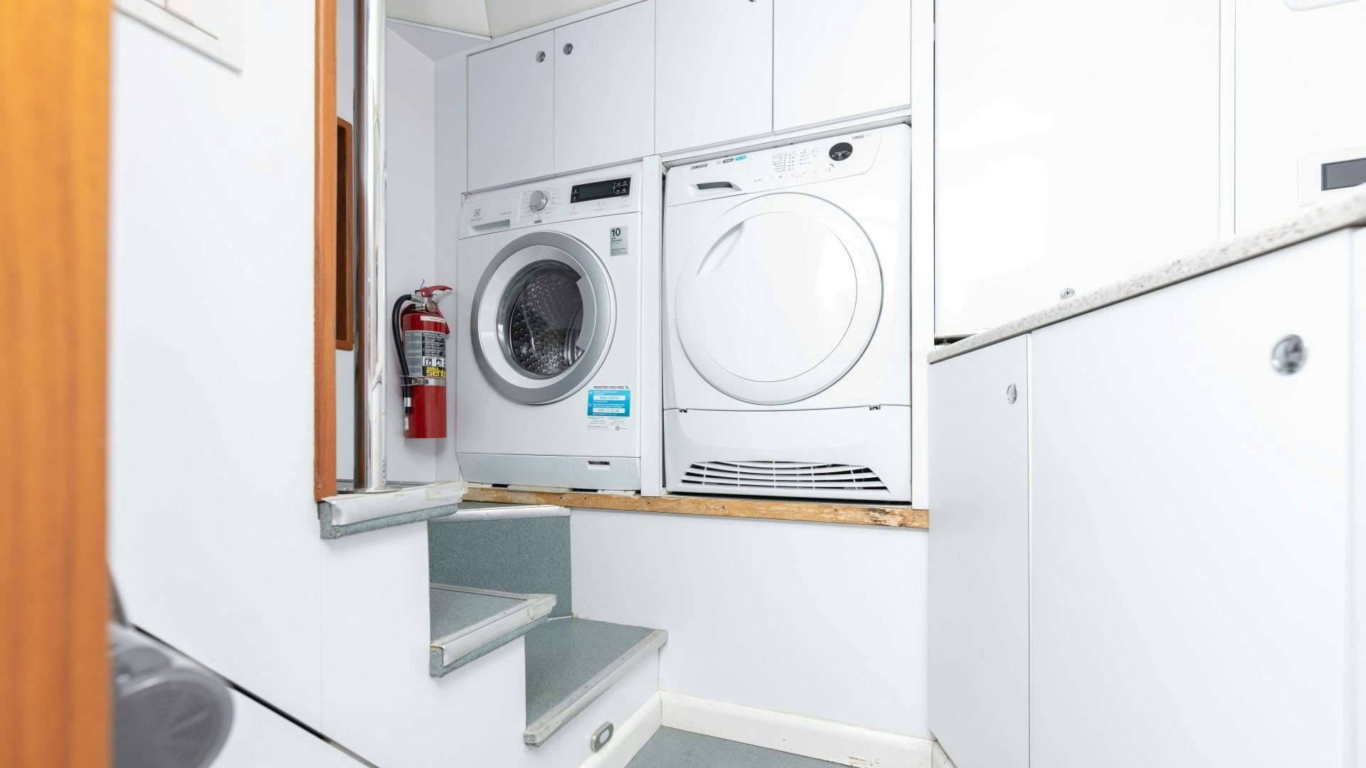 a white laundry room with a washing machine and dryer aboard THE PEARL Yacht for Sale
