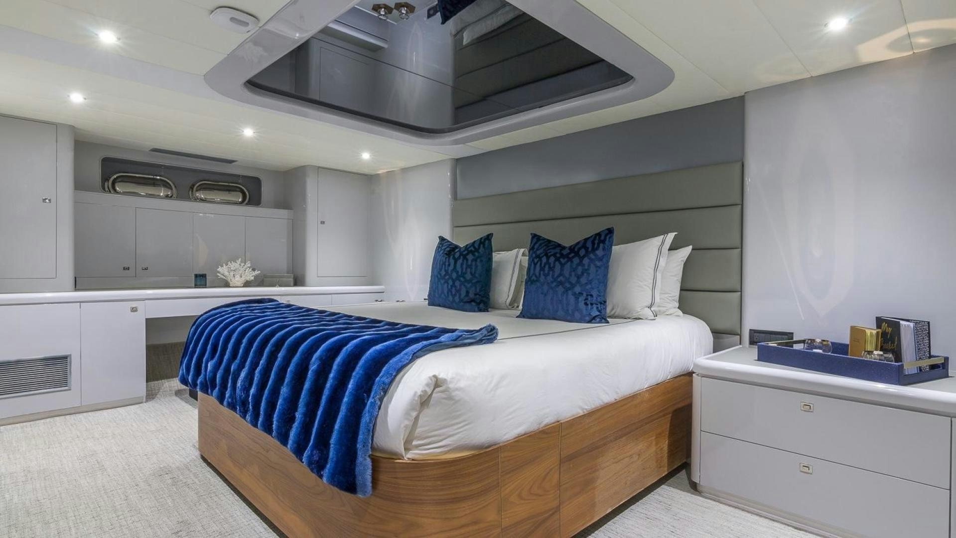 a white bedroom with a blue bed aboard NIRVANA Yacht for Sale