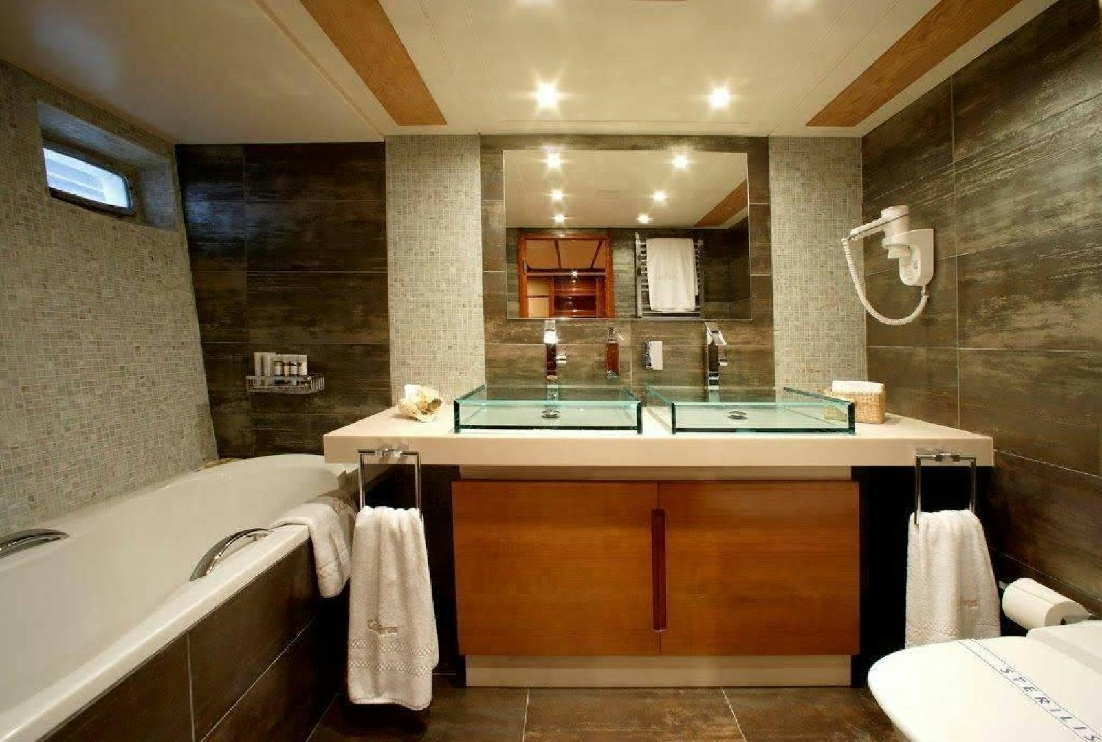 a bathroom with a tub sink and a mirror aboard CORVUS Yacht for Sale