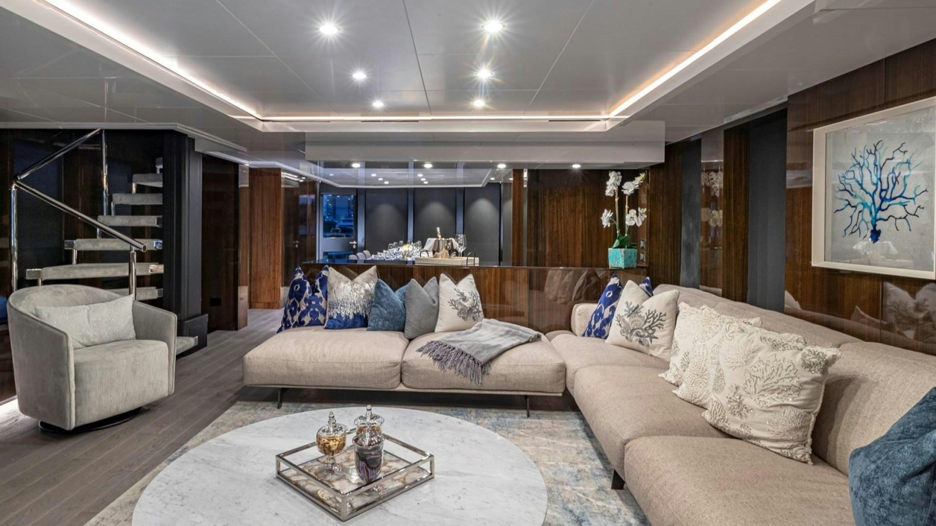 a living room with a large sectional sofa and a coffee table aboard OCULUS Yacht for Sale