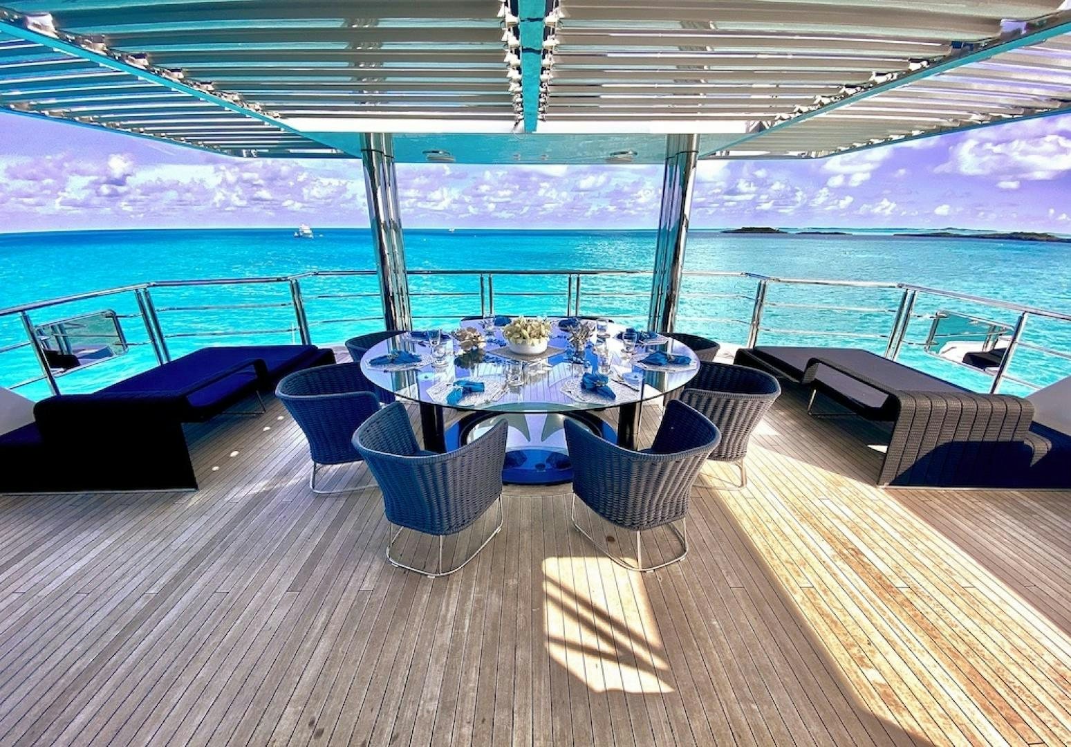 a table set on a deck overlooking a body of water aboard OCULUS Yacht for Sale