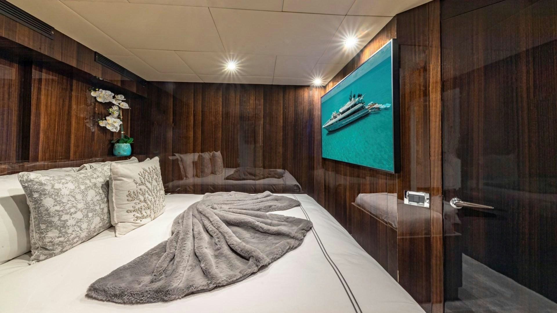 a bed with a white sheet and pillows in a room with wood walls aboard OCULUS Yacht for Sale