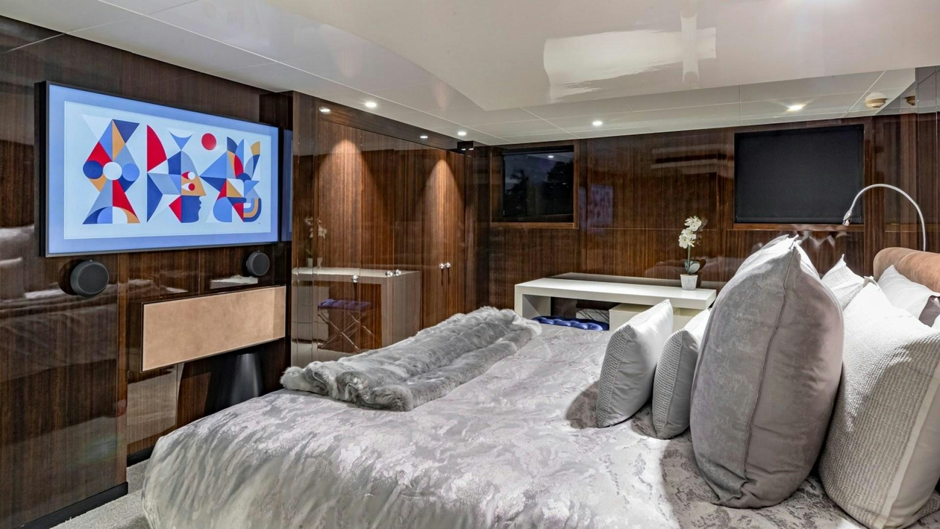 a bed with a television on the wall aboard OCULUS Yacht for Sale