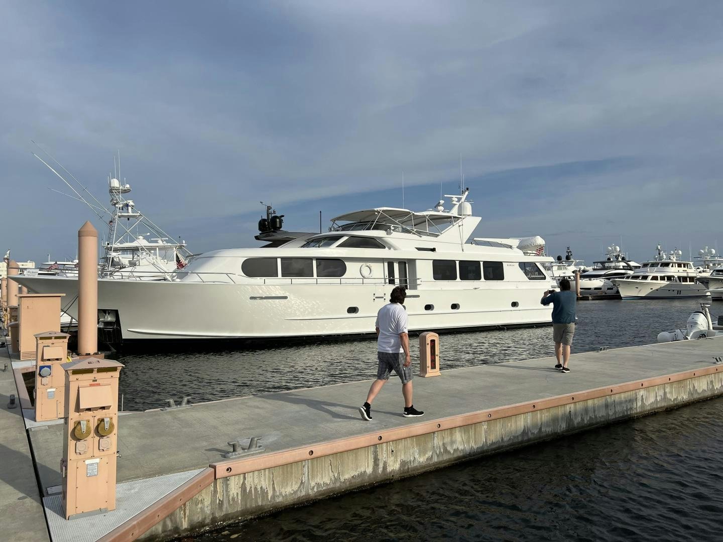 a person walking on a dock next to a large white boat aboard MY LADY ALASKA Yacht for Sale