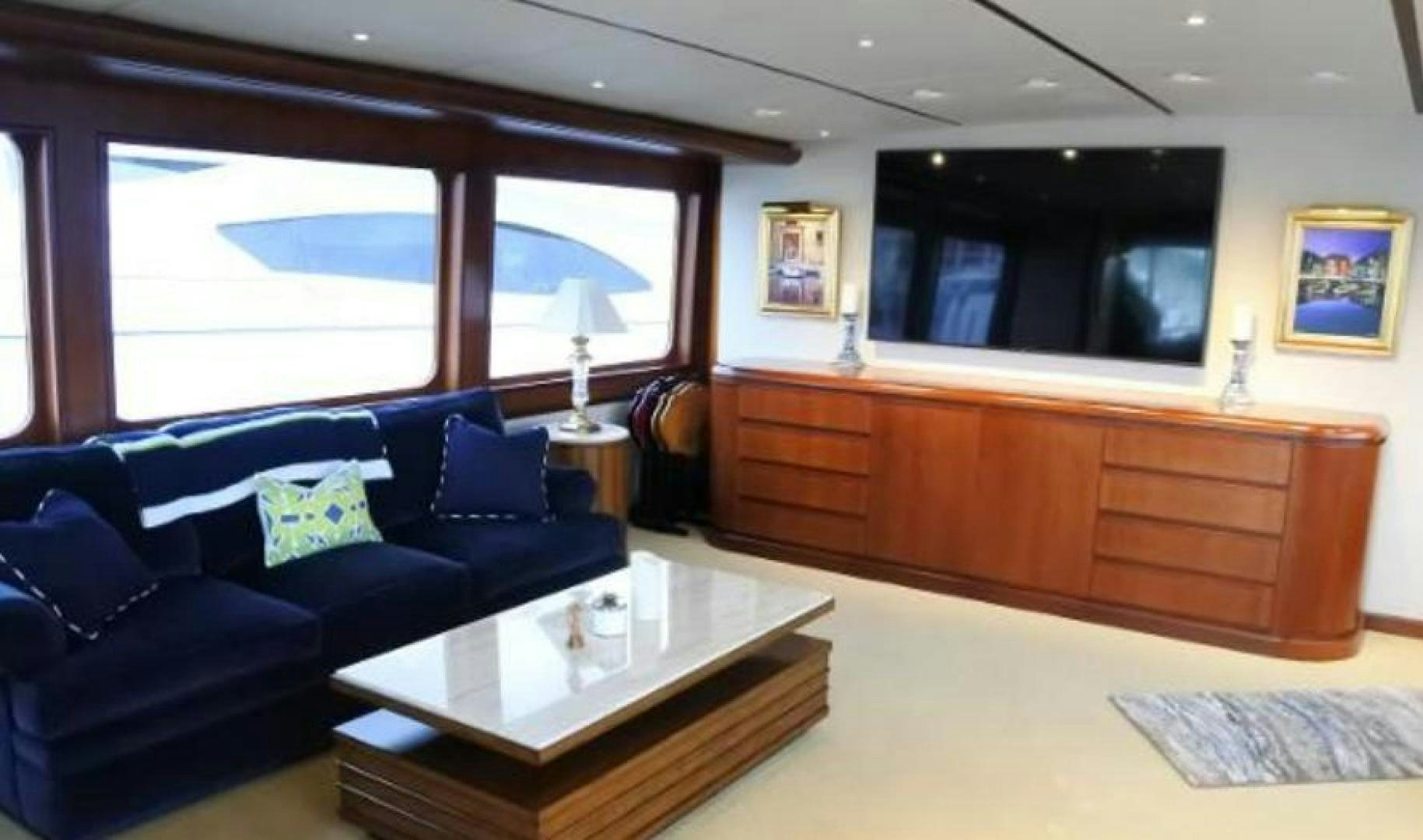 a living room with a blue couch and a large window aboard MY LADY ALASKA Yacht for Sale
