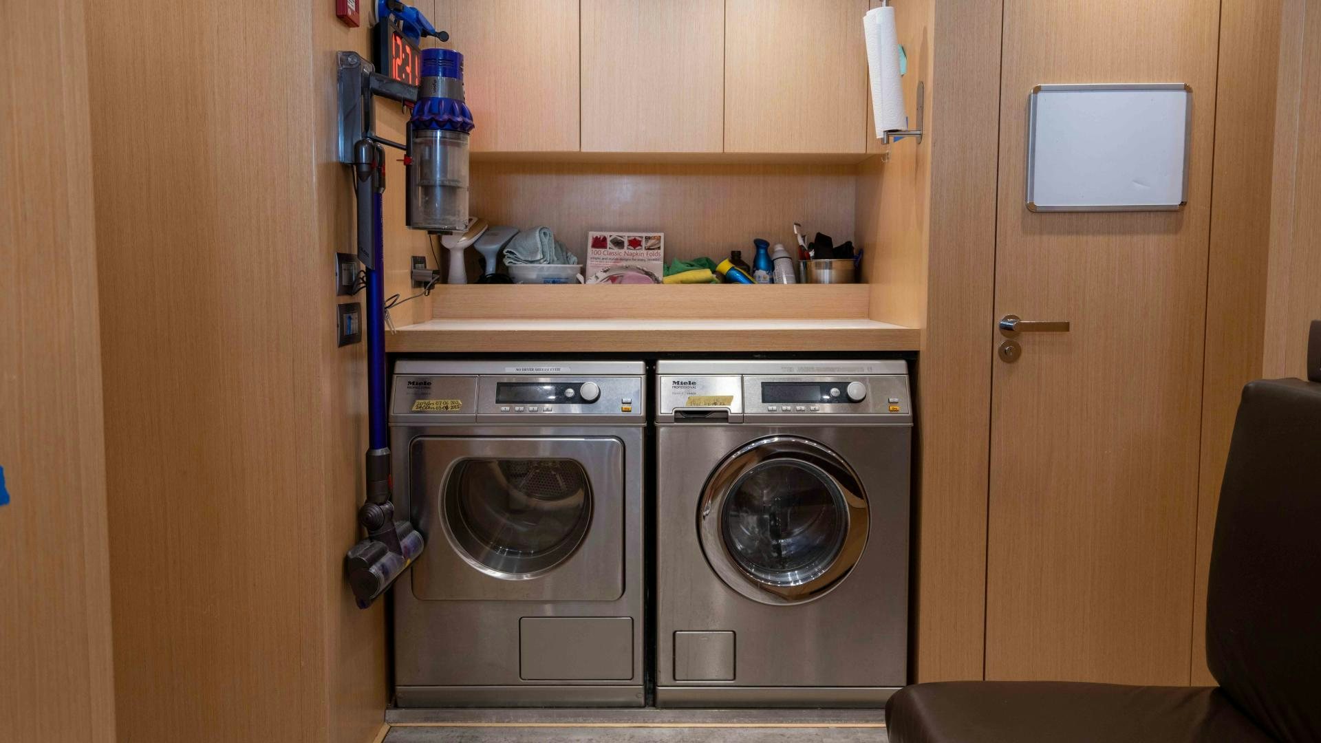 a room with a washer and dryer and a shelf with a chair and a door and aboard NOTORIOUS Yacht for Sale