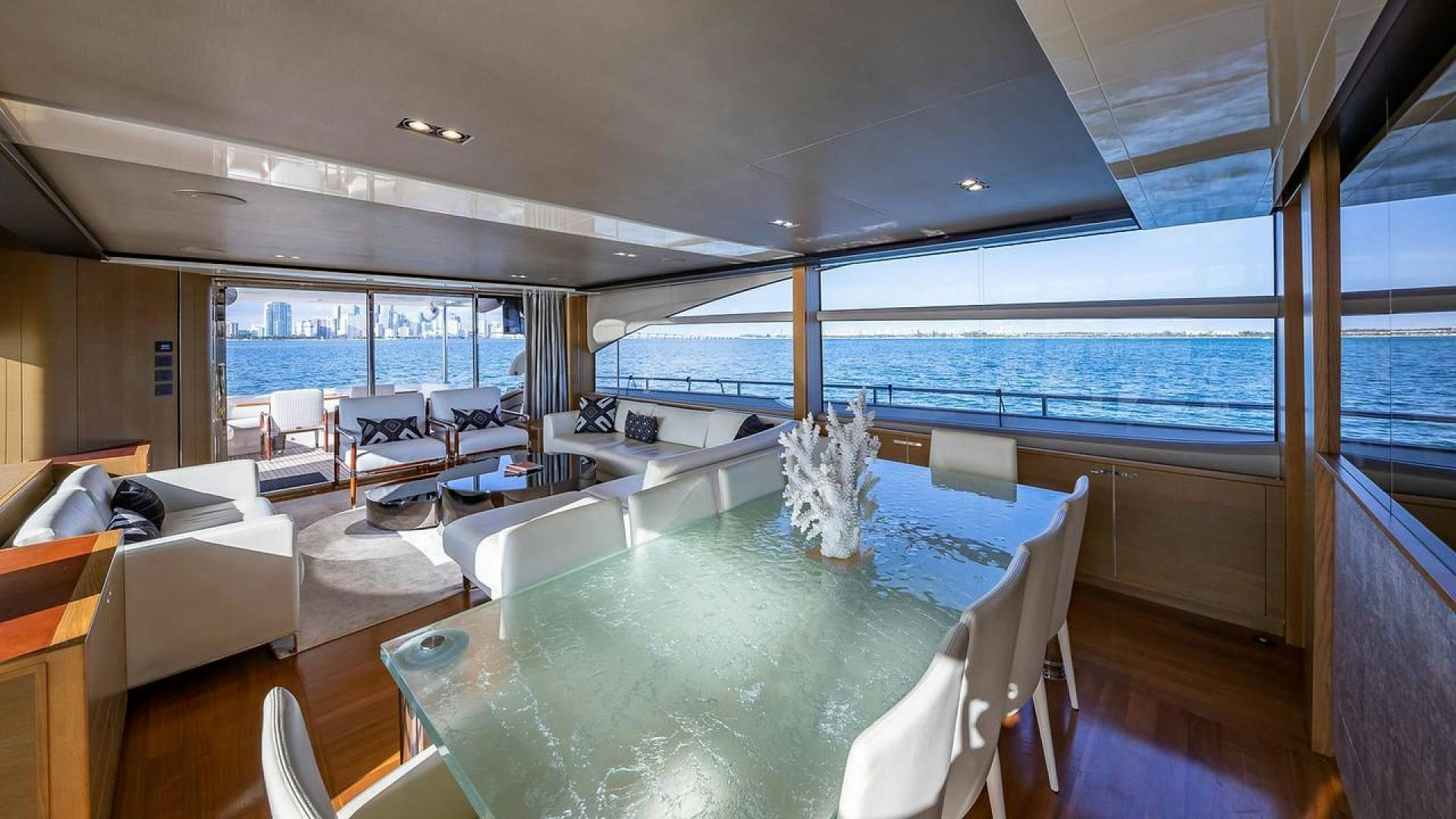 a large living room with a large glass table and a large window aboard FREEDOM Yacht for Sale